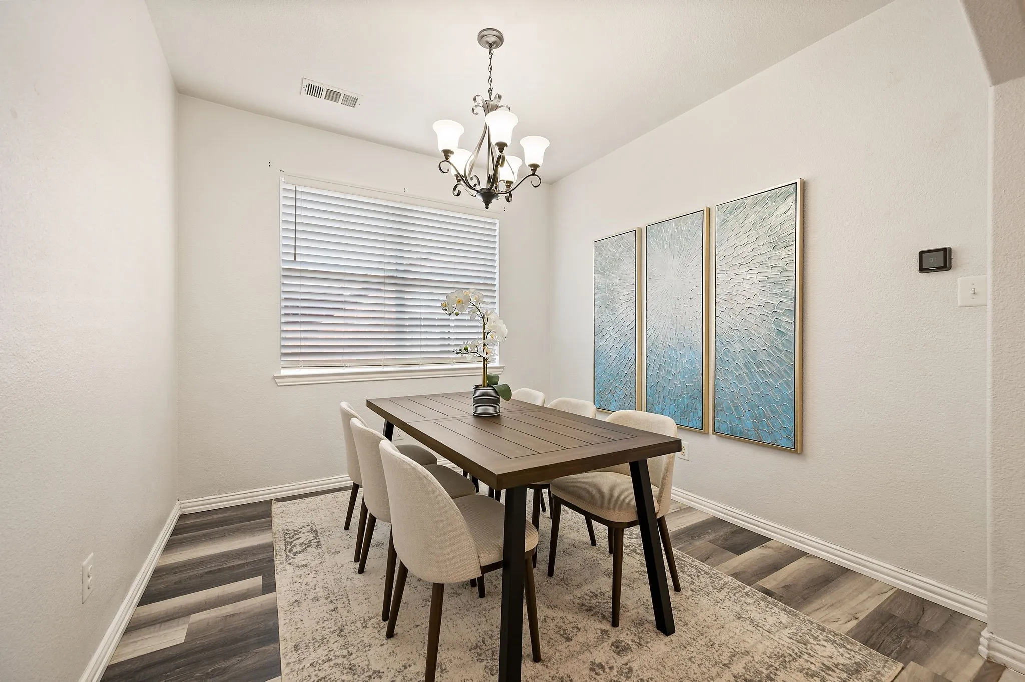 Bold windows with blinds, wood-finish flooring, and a decorative chandelier