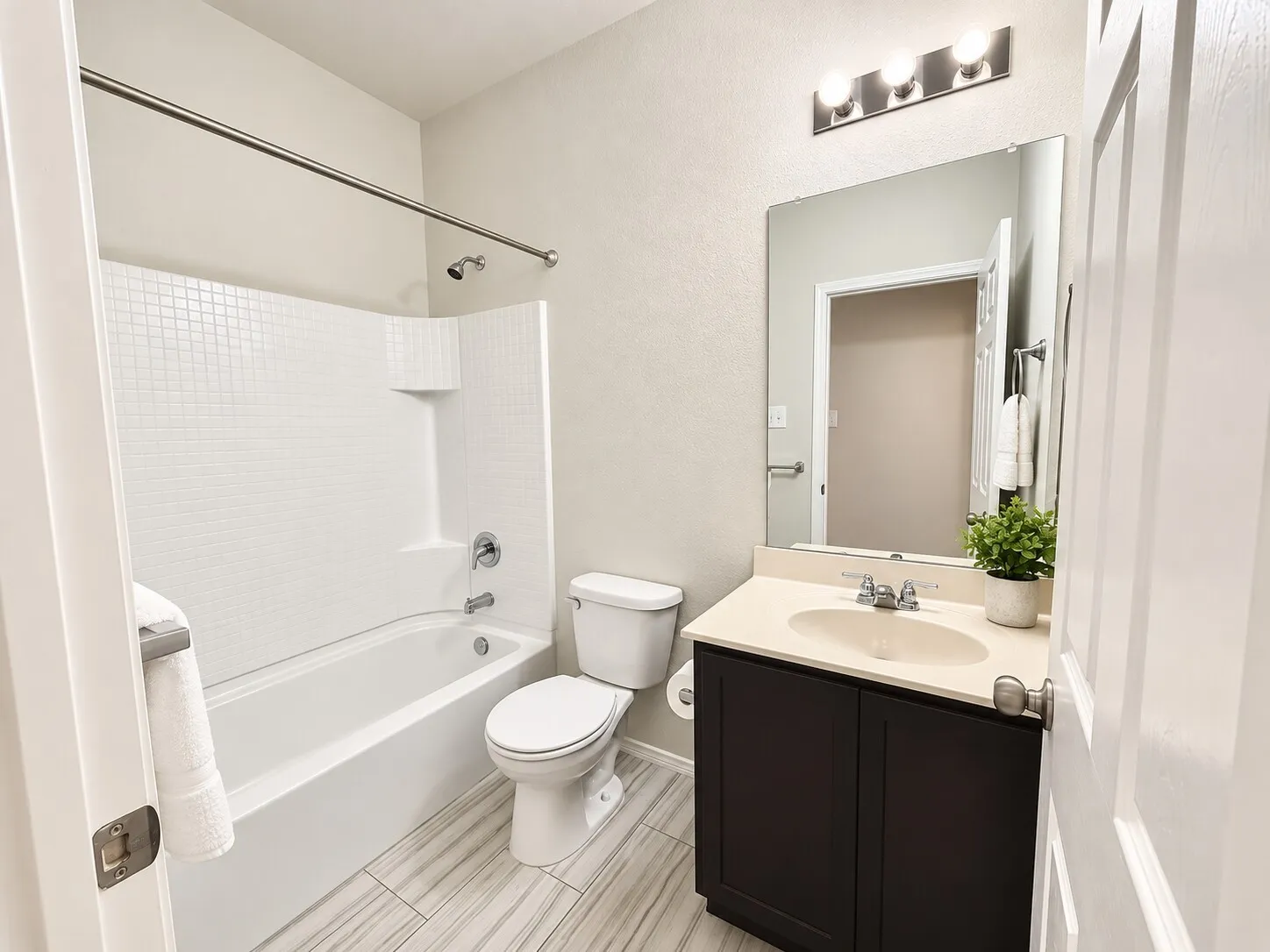 Bathroom featuring a full vanity with a built-in sink, an overhead light fixture, a toilet, and a shower-tub combination with a tiled surround