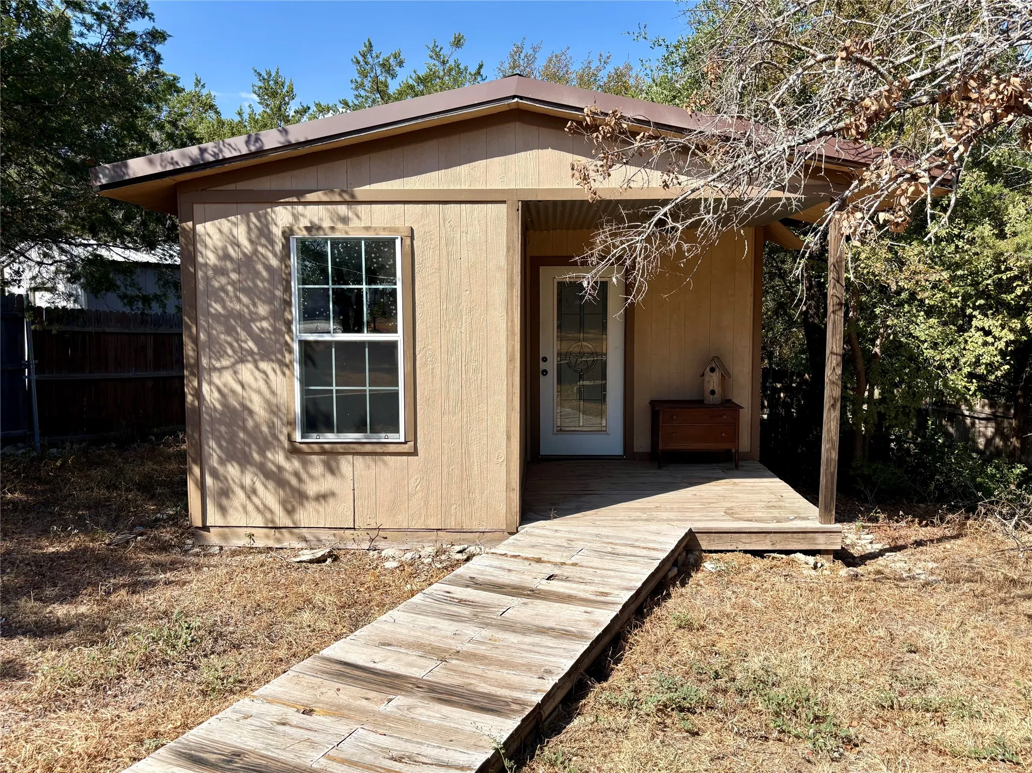 She / He Shed,  featuring a metal roof and an attached porch with a wood walkway