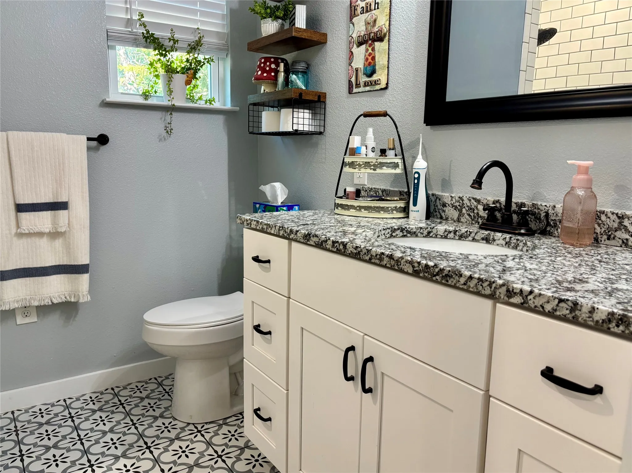 White vanity with black hardware, granite countertop, undermount sink, and matte black faucet