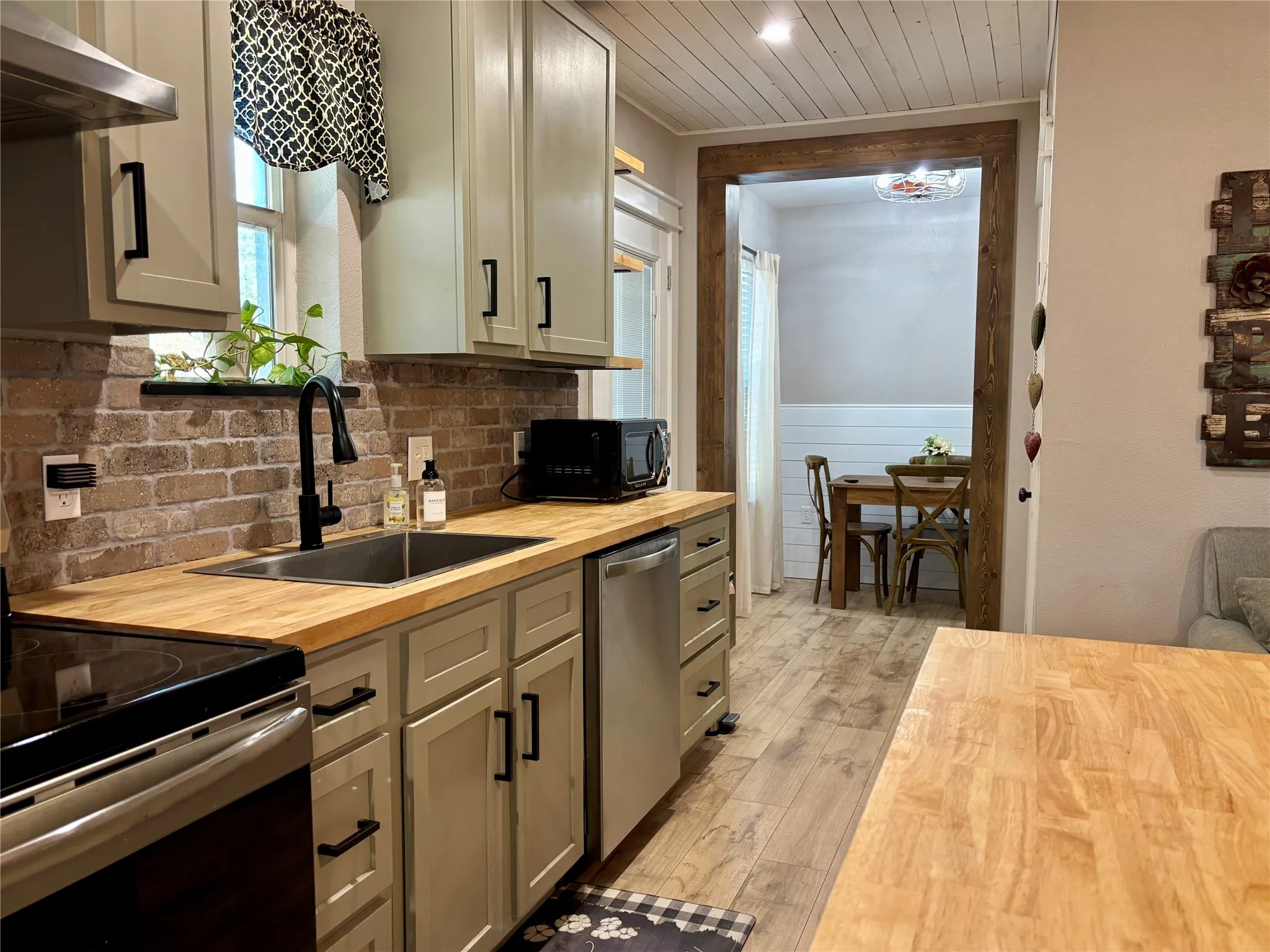 Kitchen featuring wood-finish countertops, brick backsplash, and stainless steel appliances