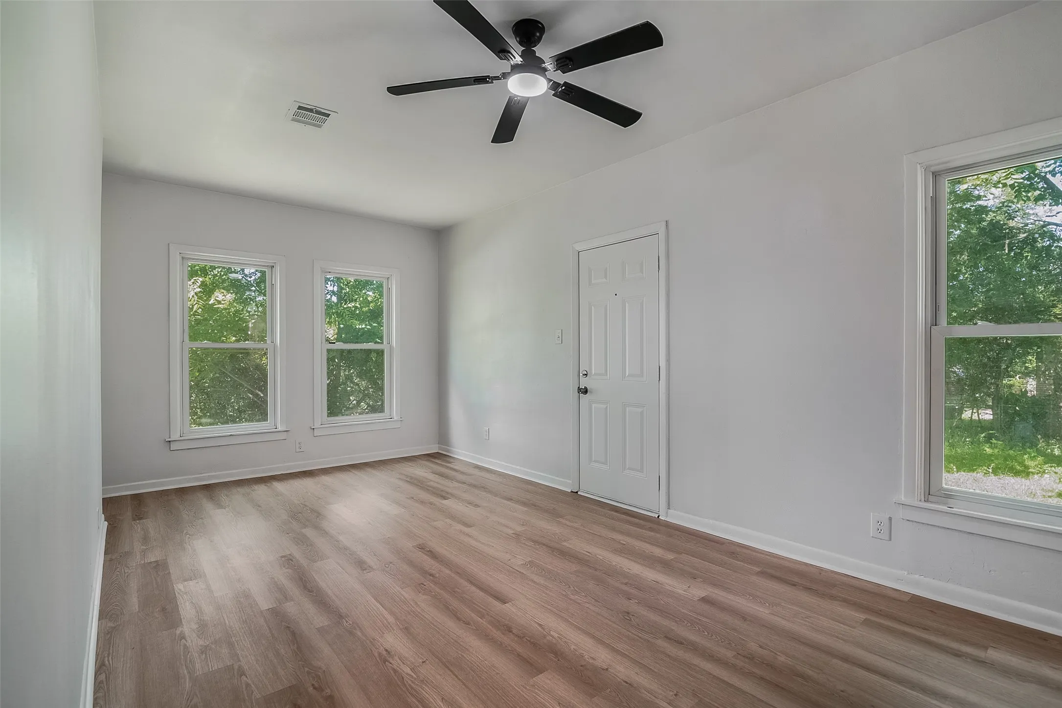 Wood-finish flooring, white walls, and a ceiling fan with integrated lighting