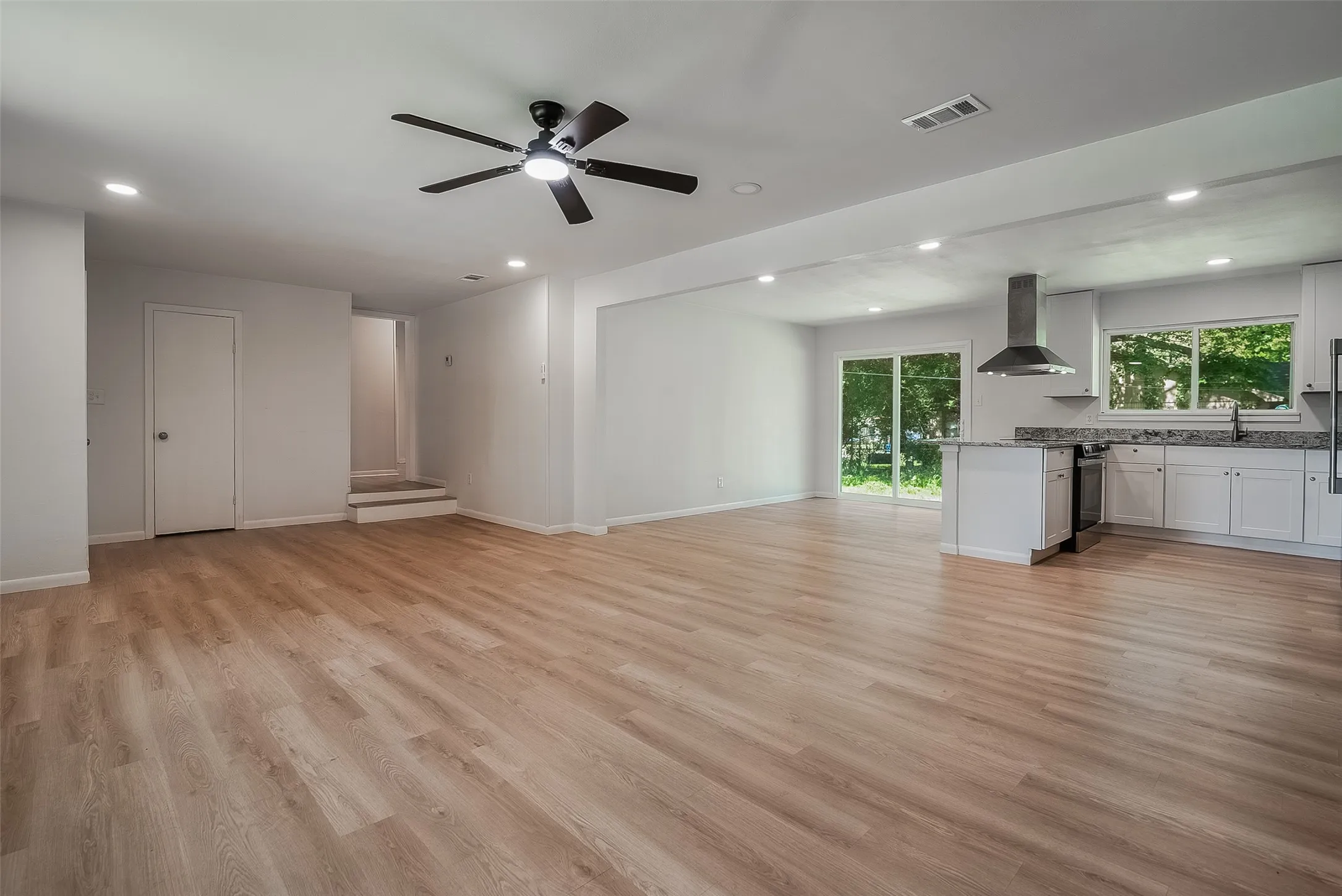 Open-concept living space with wood-finish flooring, recessed lighting, and a ceiling fan