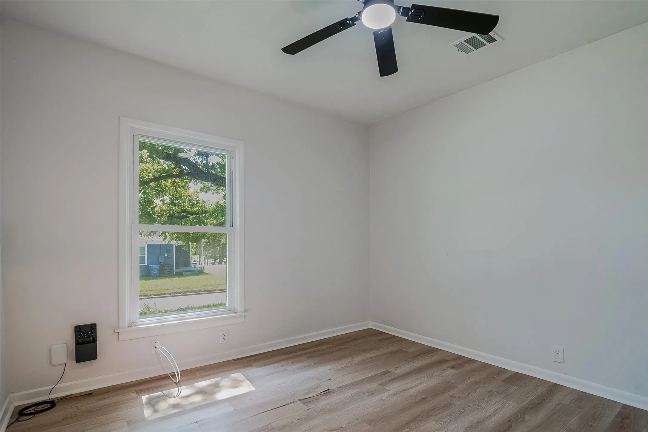 Wood-finish flooring, white walls, and a ceiling fan with integrated lighting