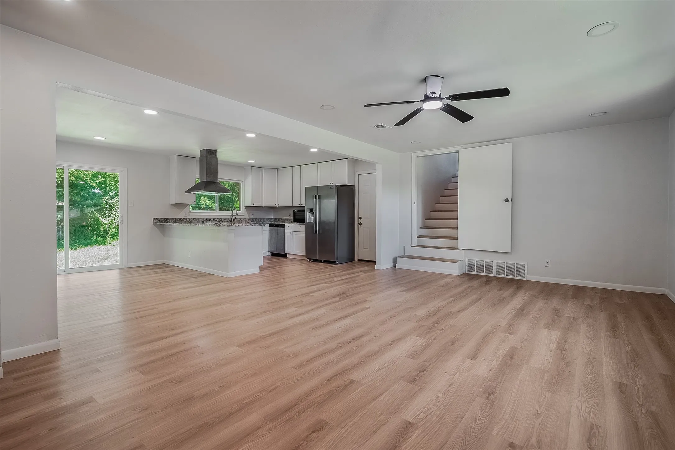 Open-concept living area with wood-finish flooring, recessed lighting, and a ceiling fan