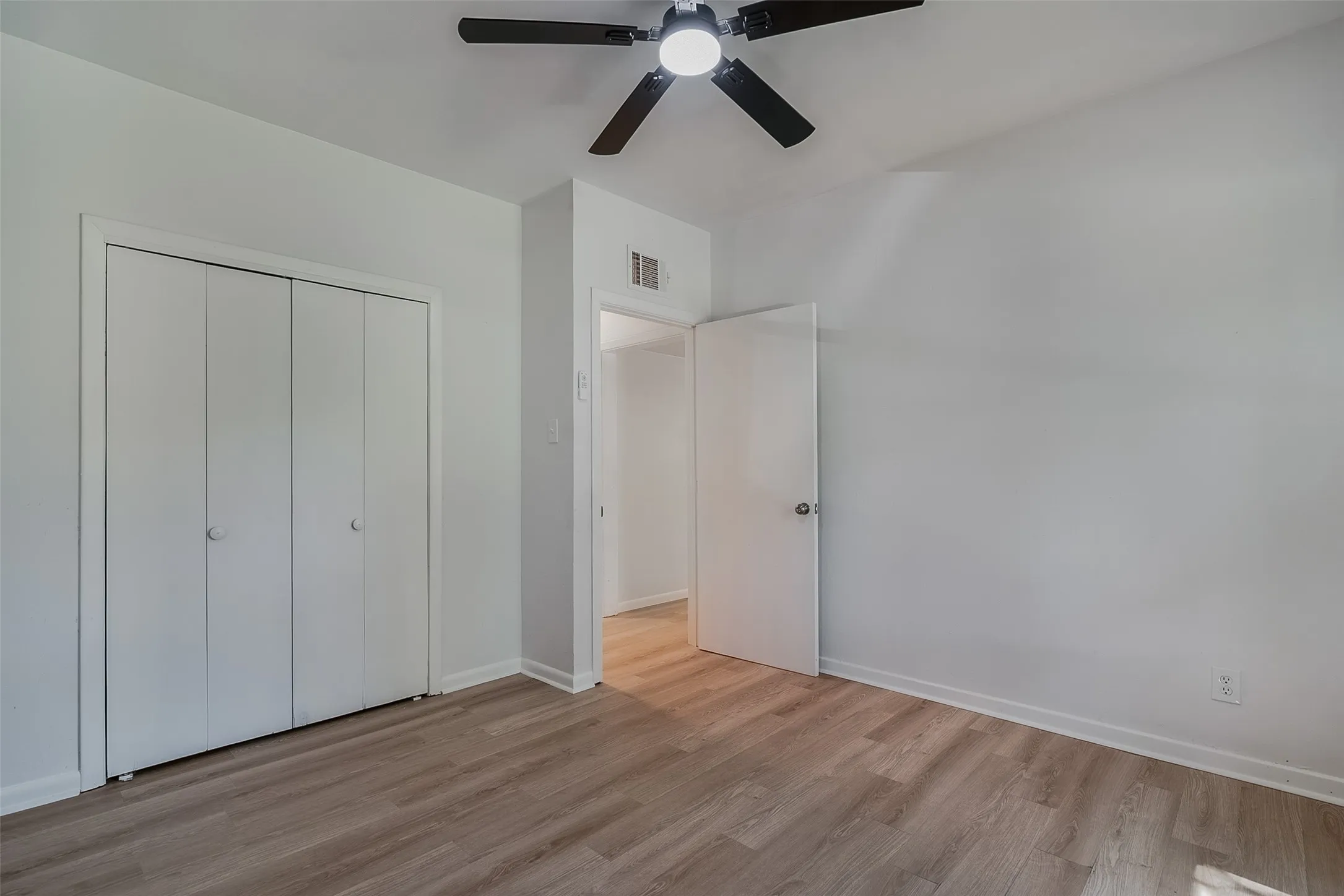 Neutral wall color, wood-finish flooring, ceiling fan, and bi-fold closet doors