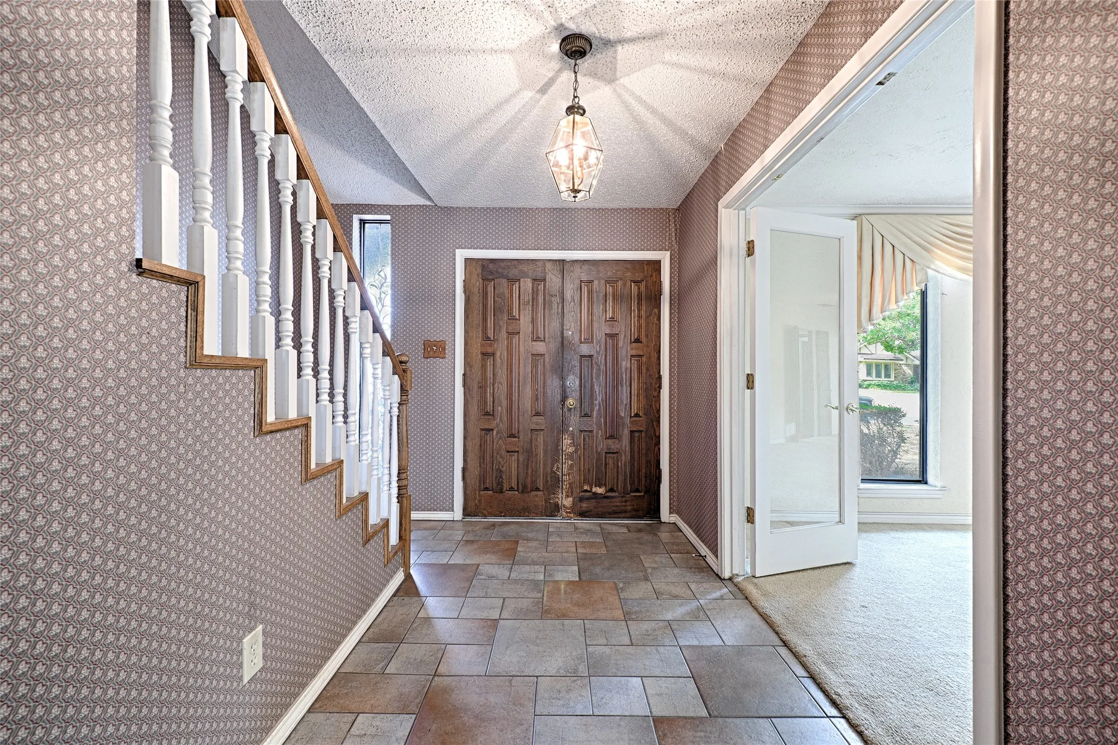 Foyer featuring tile flooring, a staircase with white balusters, a decorative chandelier, and double entry doors