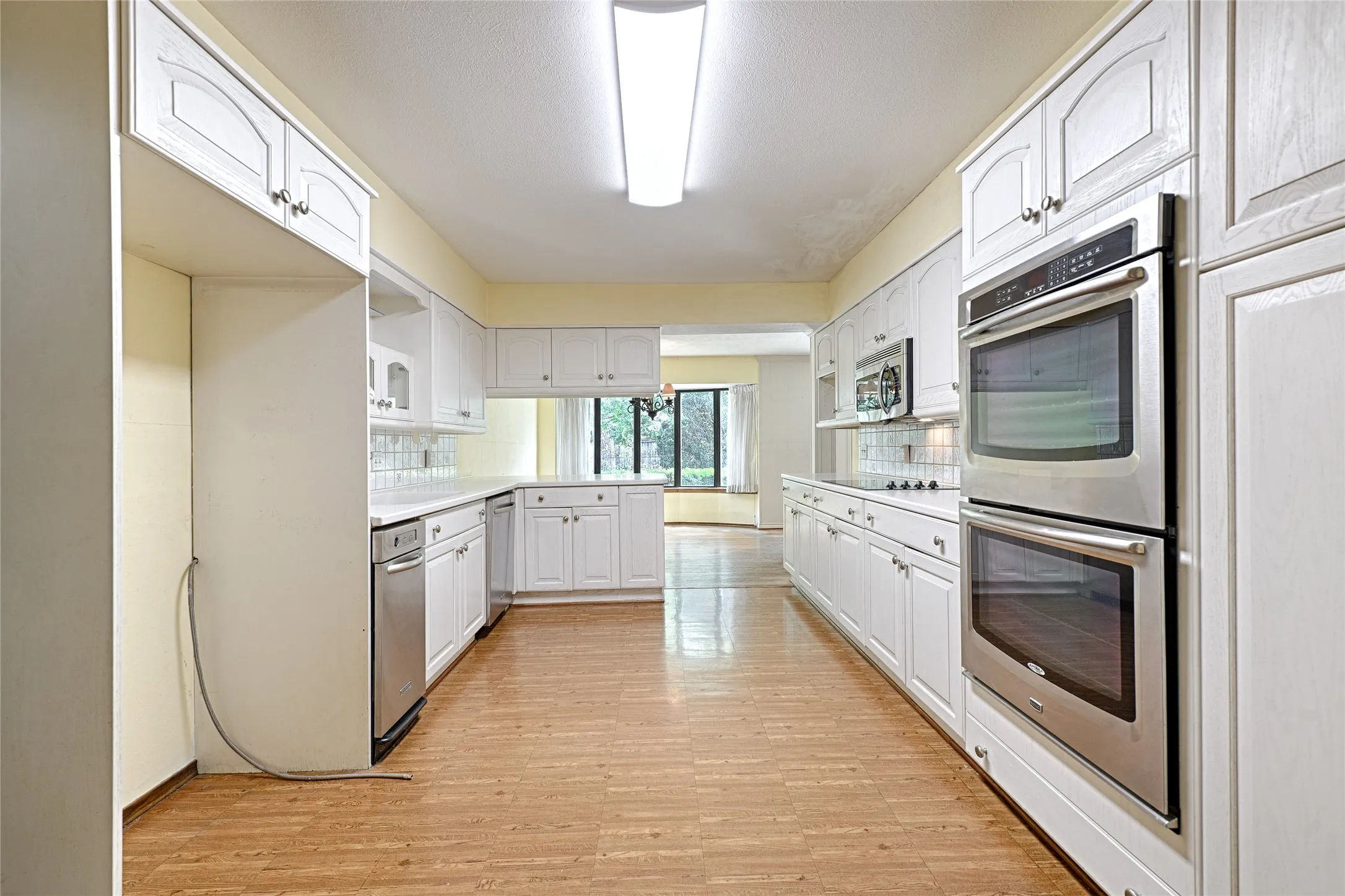 Recessed lighting and wood-finish flooring complement the white cabinetry