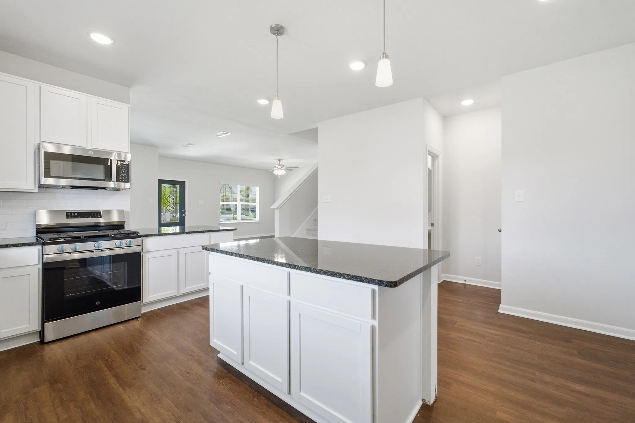 Kitchen featuring white cabinetry, dark countertops, stainless steel appliances, and wood-finish flooring