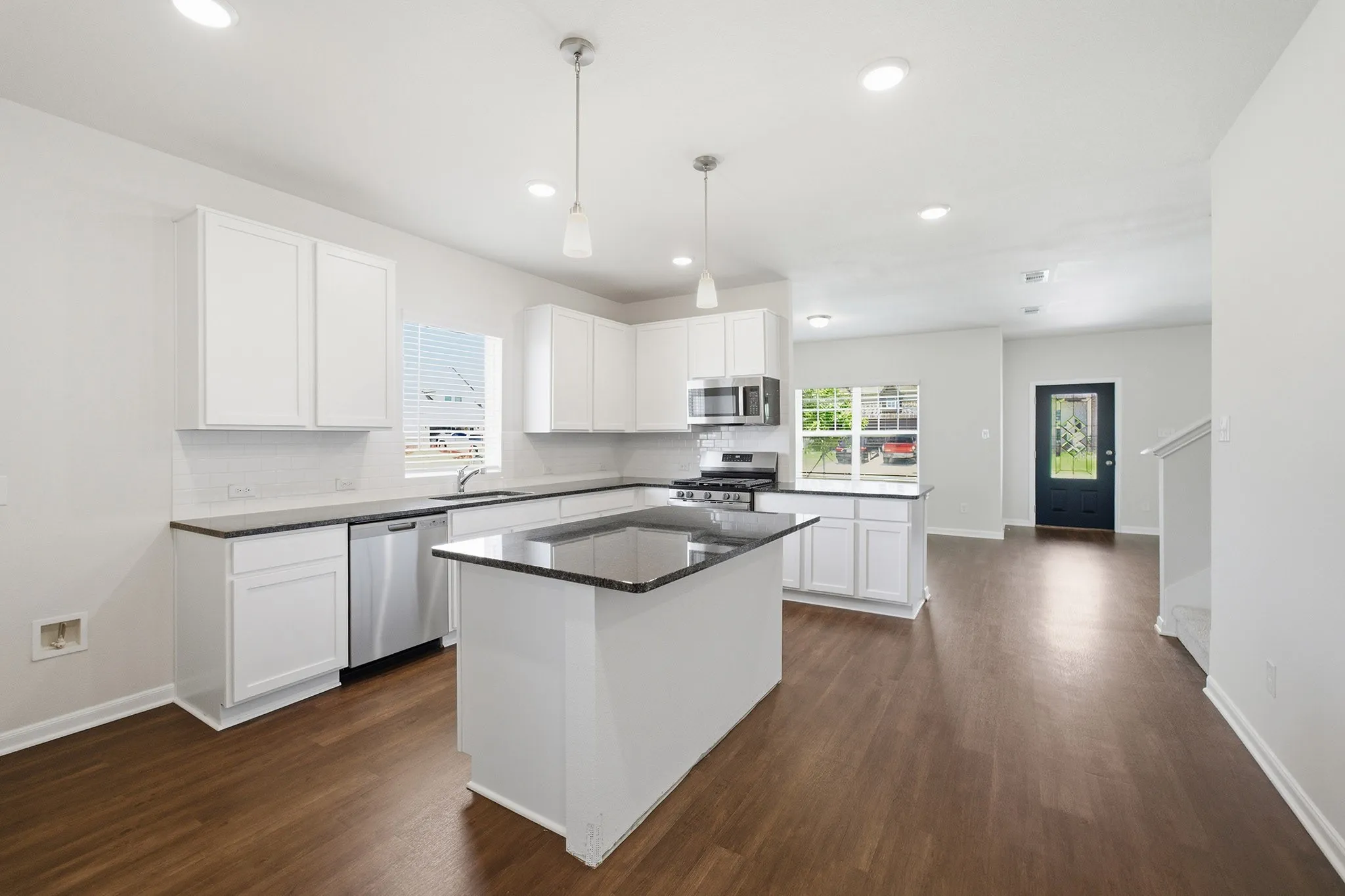 Kitchen featuring white cabinetry, dark countertops, a central island, stainless steel appliances, and wood-finish flooring