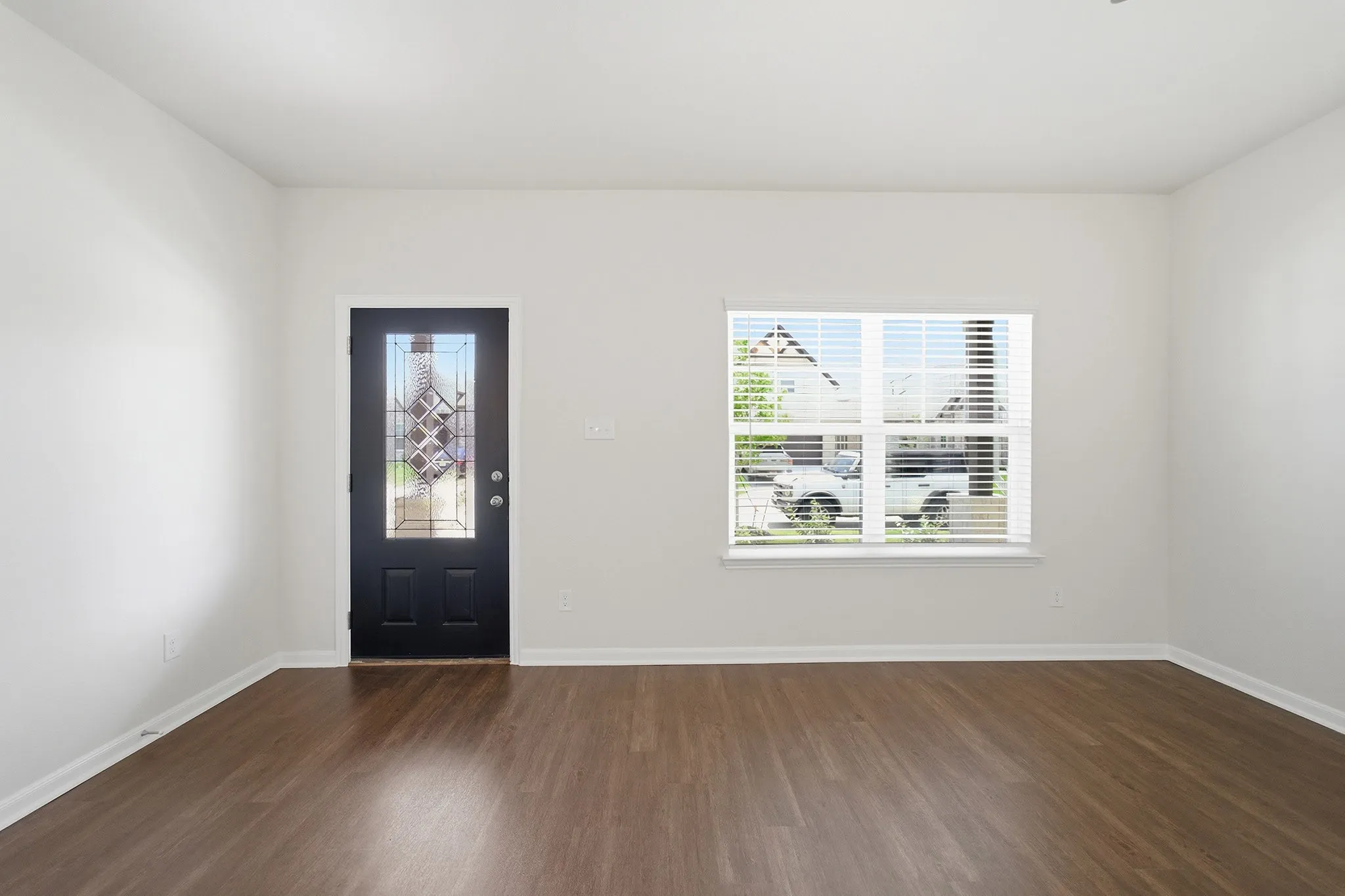 Entryway featuring a decorative glass door, wood-finish flooring, and a window with horizontal blinds