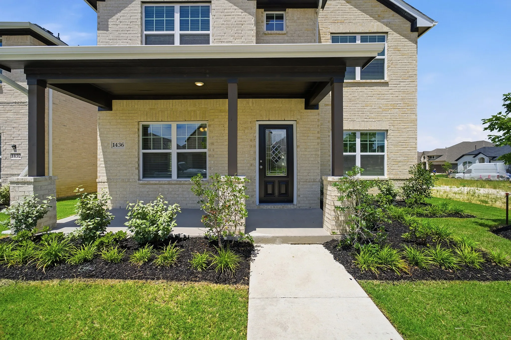 Brick exterior with a covered porch, featuring dark-stained wood posts and a concrete walkway