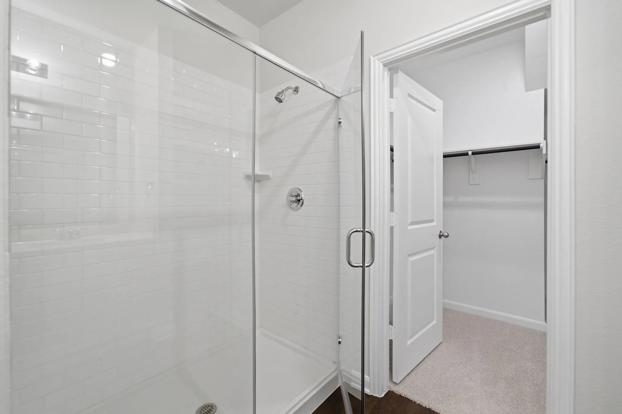 Glass-enclosed shower with subway tile surround, chrome fixtures, and a built-in shelf
