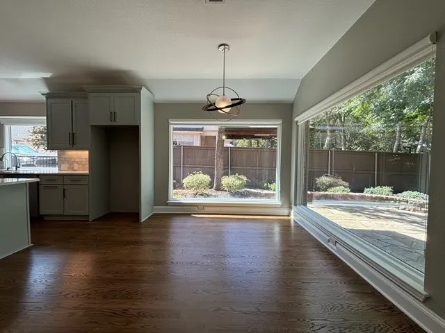 Hardwood flooring throughout, modern pendant lighting, expansive window, sliding glass door, and shaker-style cabinetry