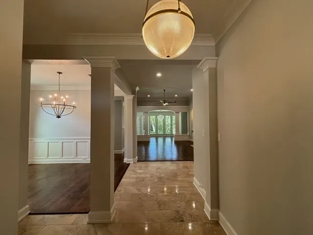 Foyer featuring polished tile flooring, a spherical pendant light, and architectural columns