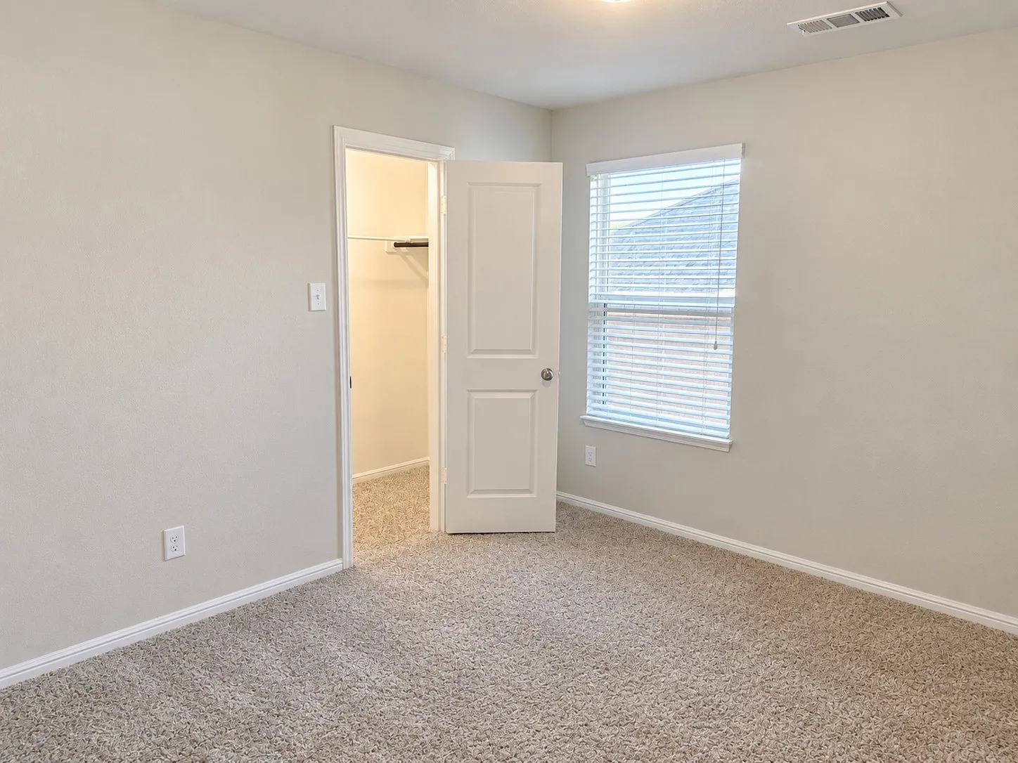 Carpeted flooring, neutral wall tones, white trim, and a built-in closet with shelving