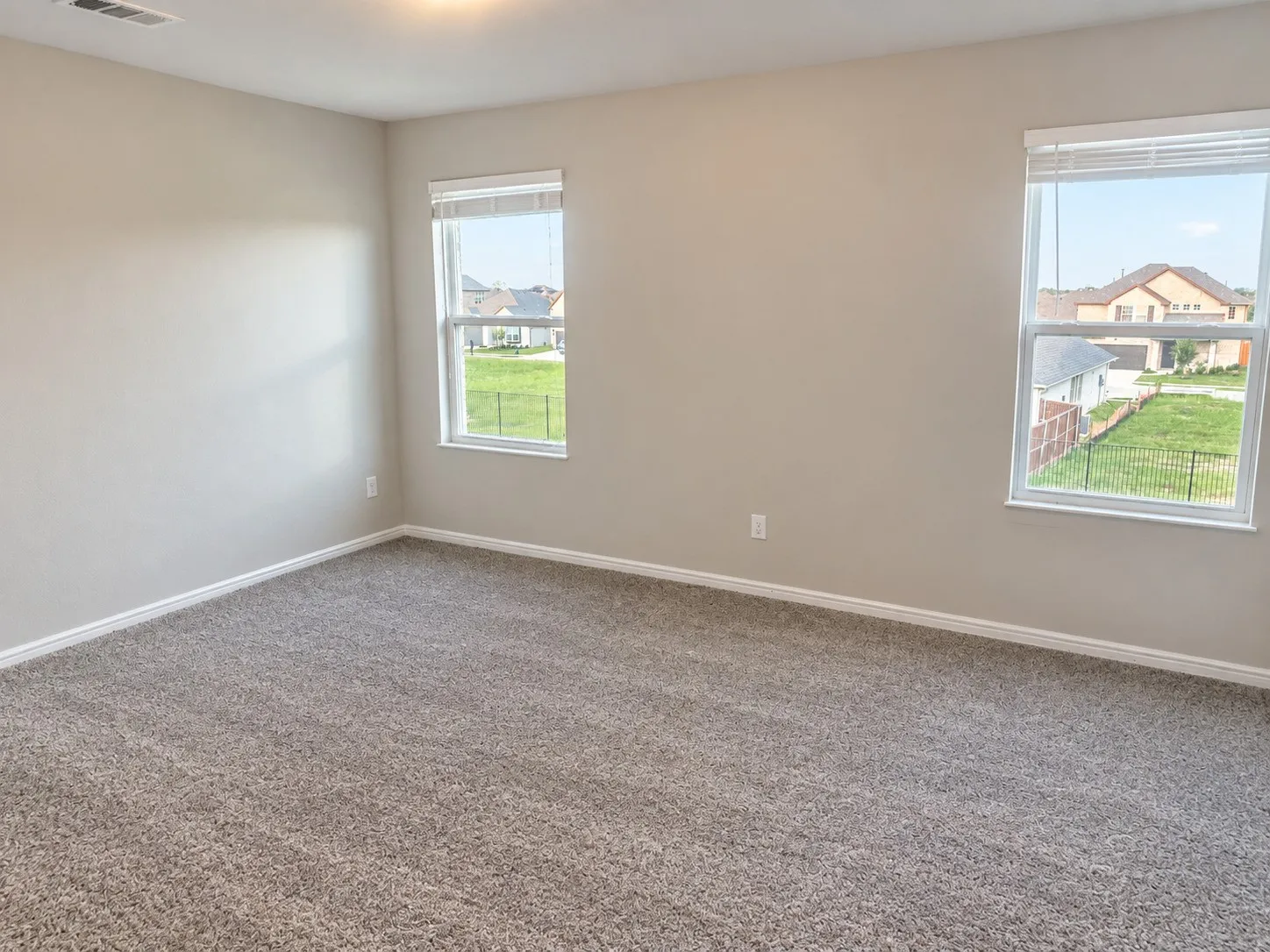 Plush gray carpet flooring, neutral paint palette, and two windows providing abundant natural light