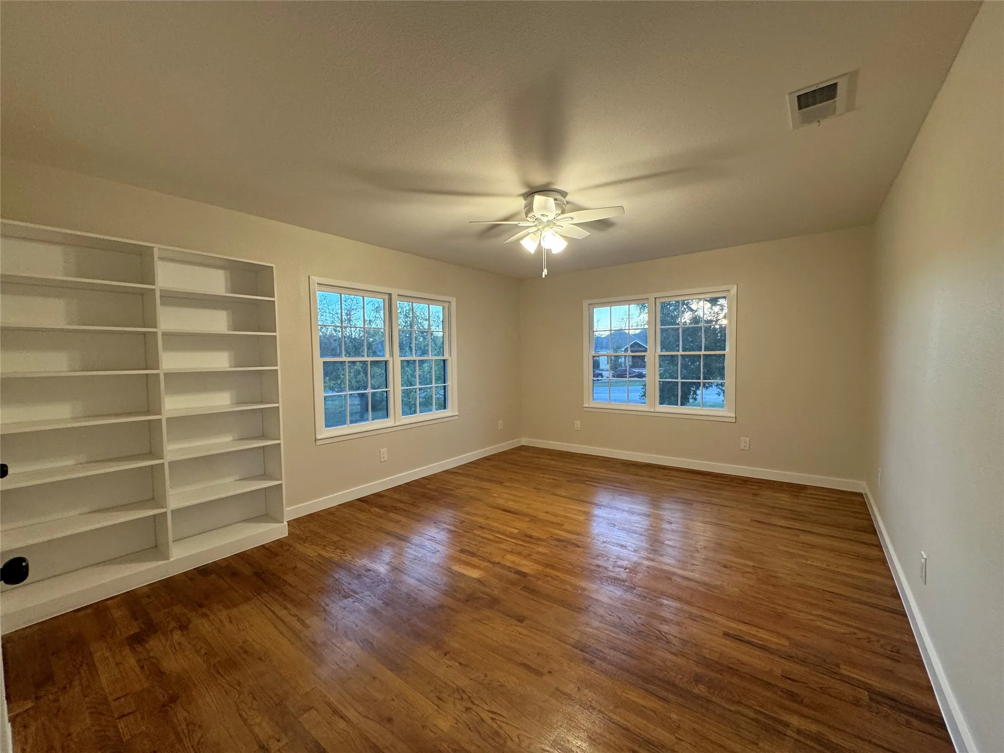 Empty room with ceiling fan and dark hardwood / wood-style floors