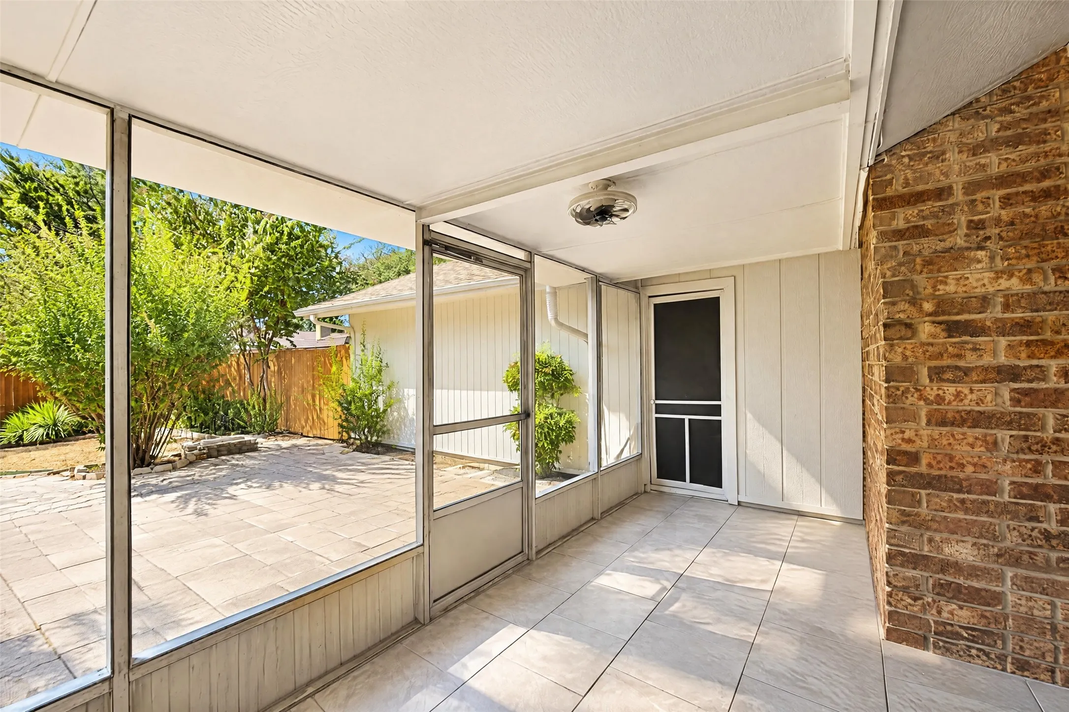 Screened enclosure featuring tiled flooring, a ceiling fan, and access to a paved outdoor area