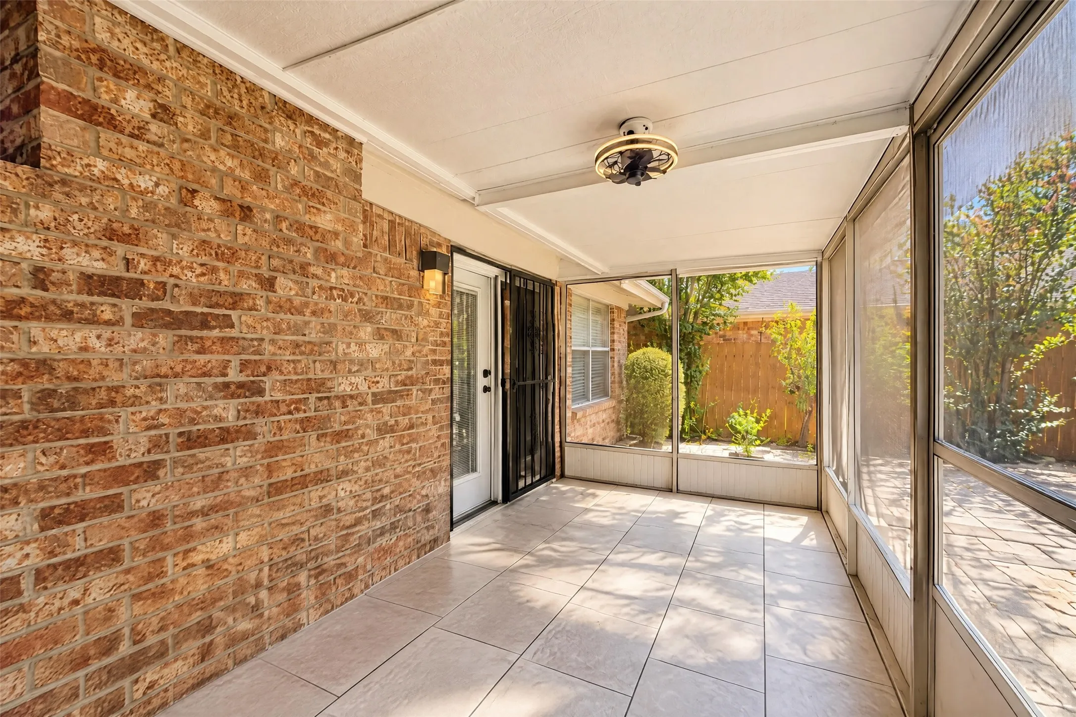 Enclosed patio featuring a brick exterior wall, tile flooring, and a ceiling-mounted light fixture