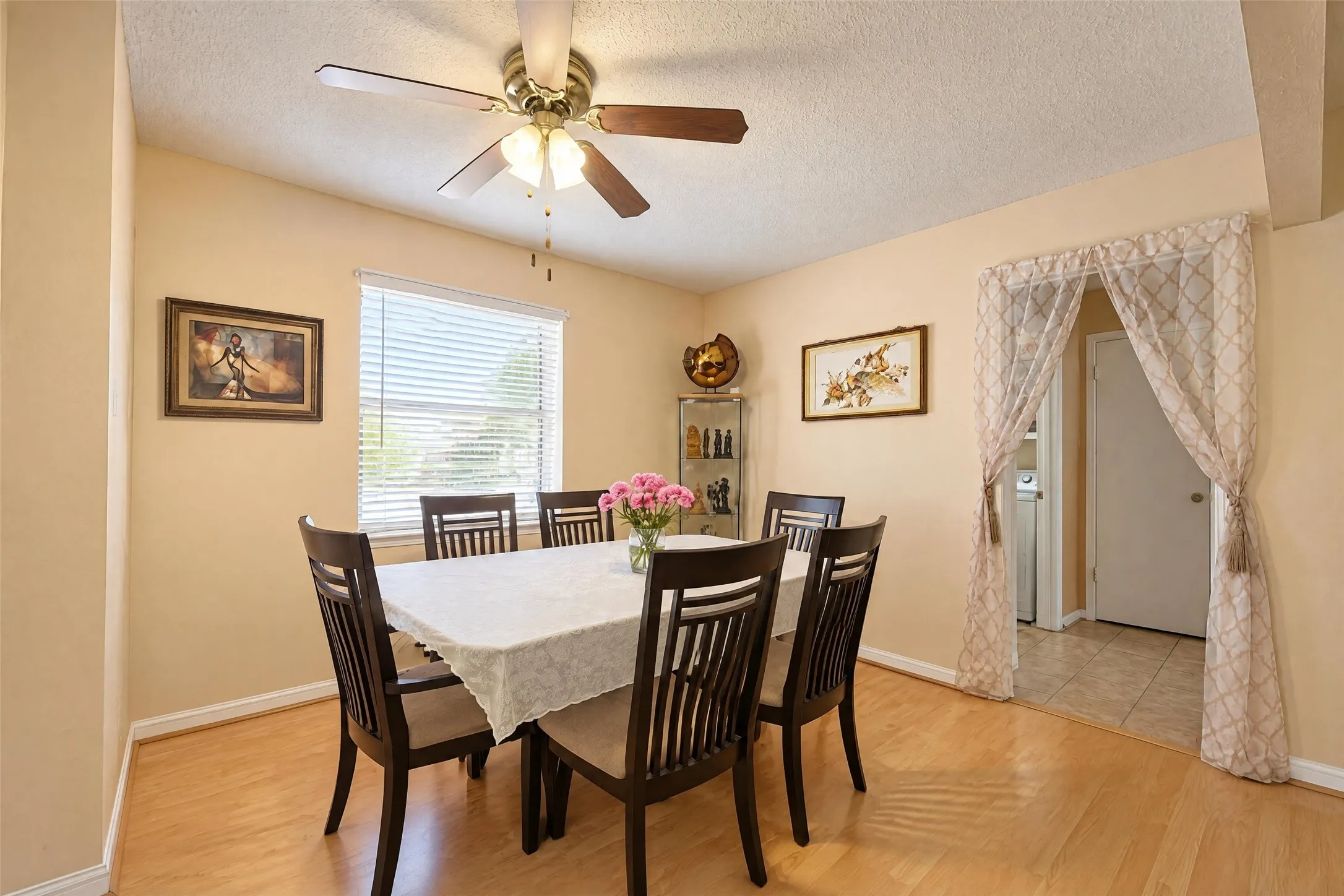 Dining area featuring wood-finish flooring, a ceiling fan with integrated lighting, and a window with blinds