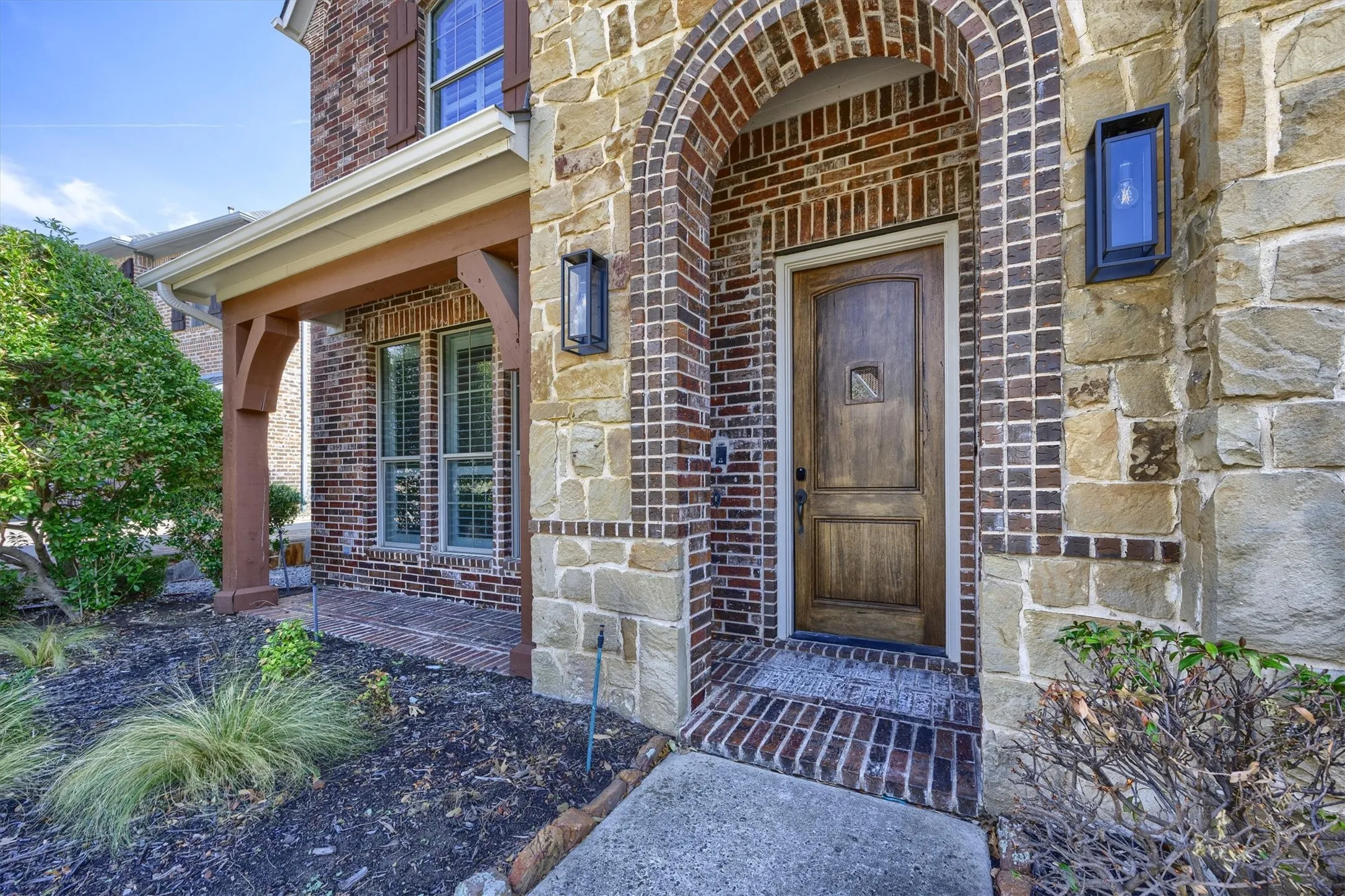 Stone and brick are mixed with a patio on the front of the home.