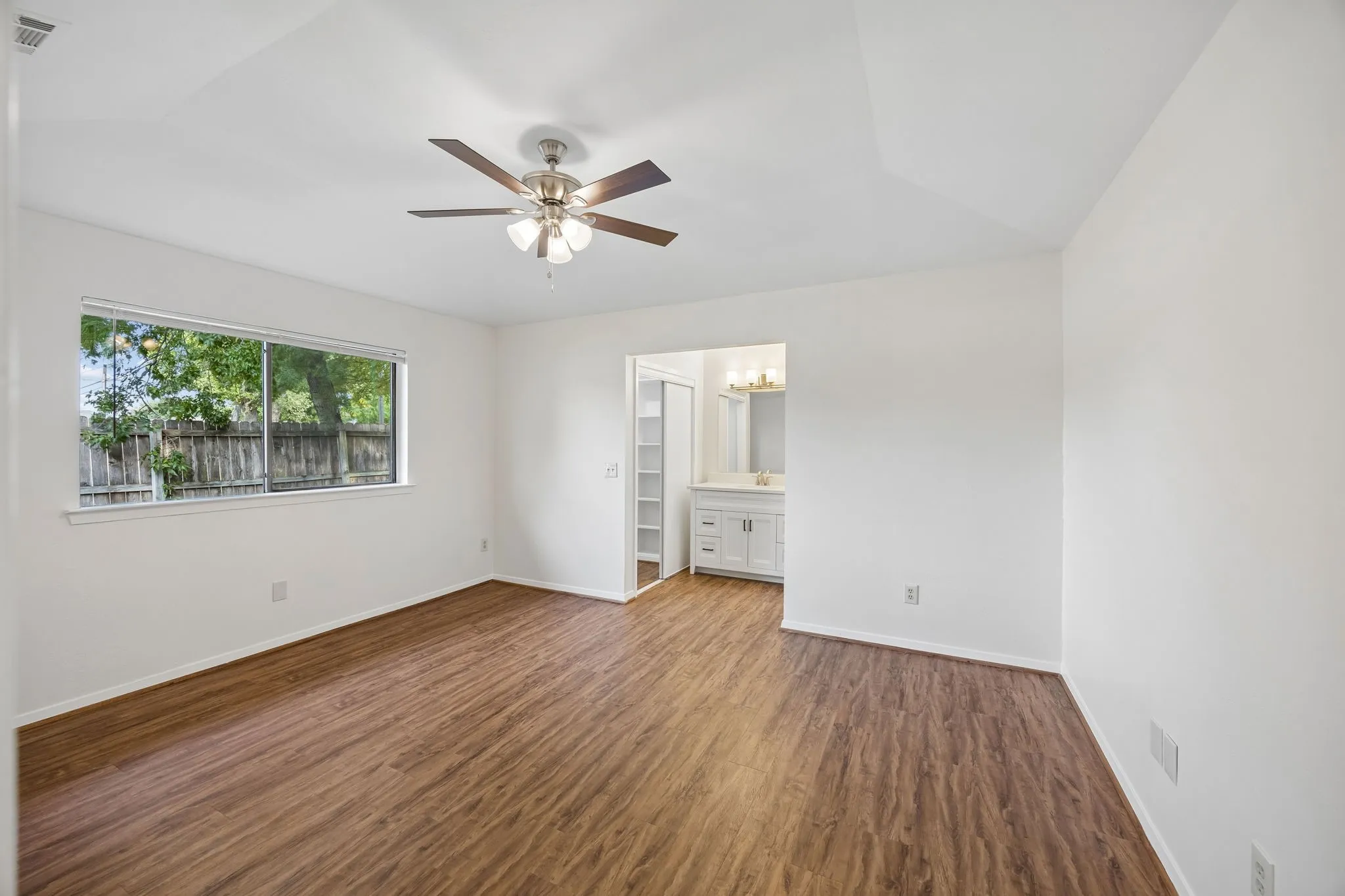 Wood-finish flooring, white walls, and a ceiling fan with integrated lighting