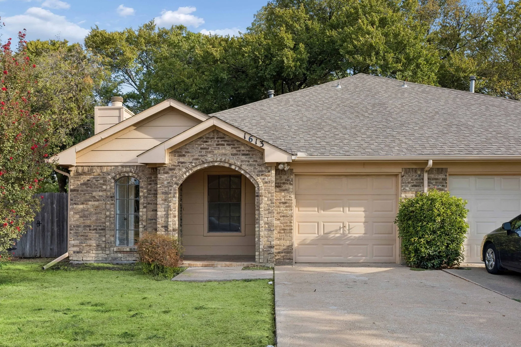 Brick exterior with an arched entry, gabled roofline, and attached garage