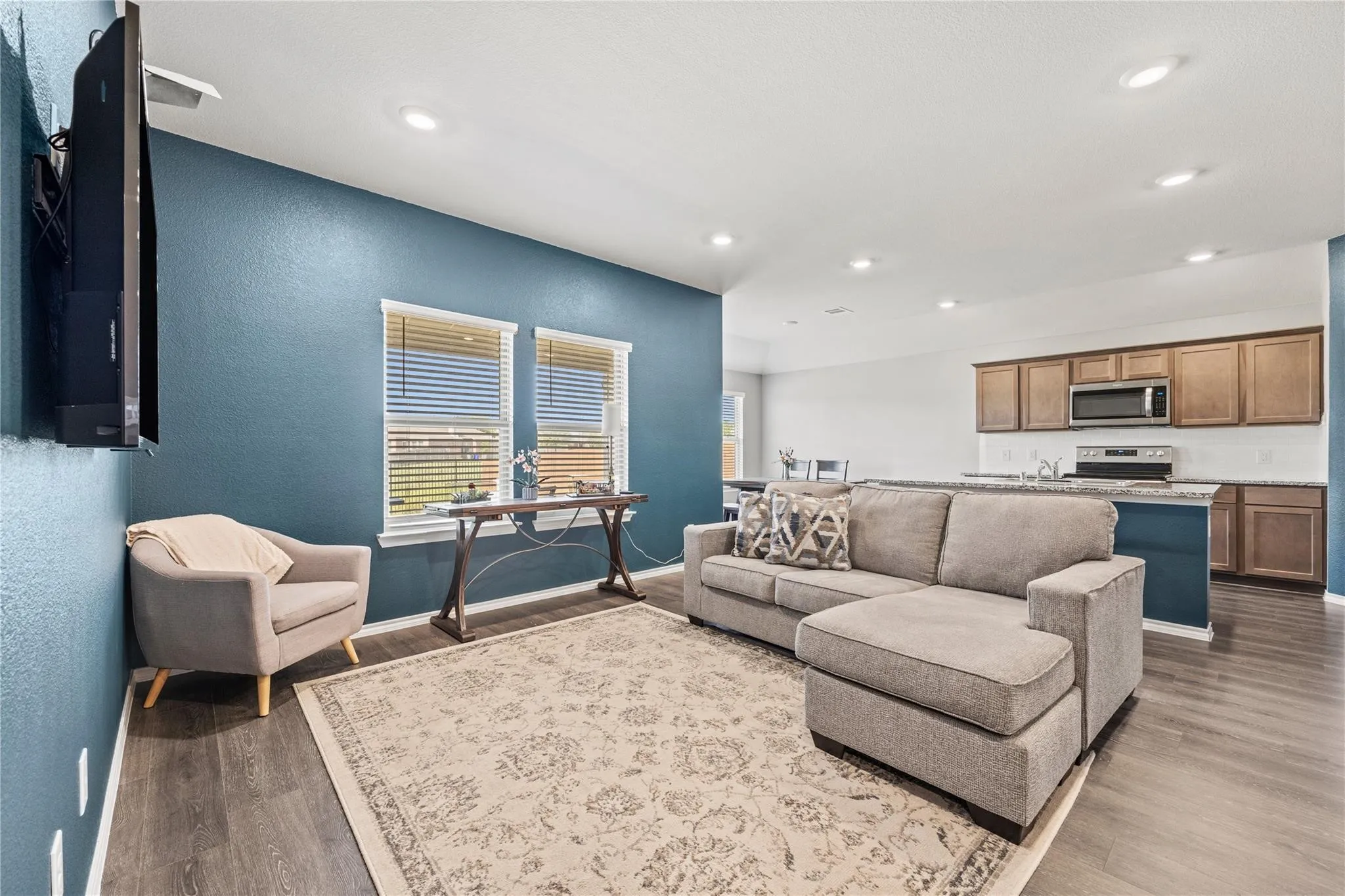 Open-concept living space featuring wood-finish flooring, recessed lighting, and windows with blinds