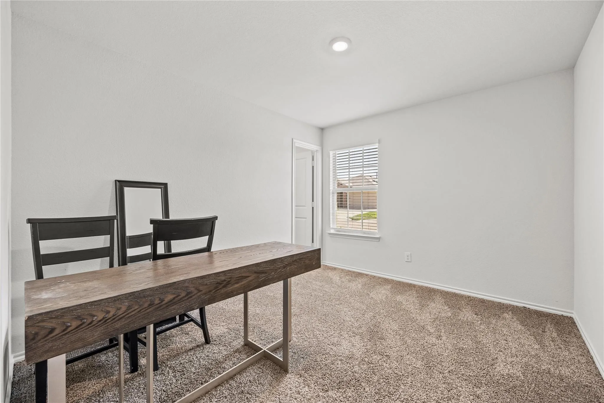 Recessed ceiling light, neutral wall paint, window with blinds, carpet flooring, interior door