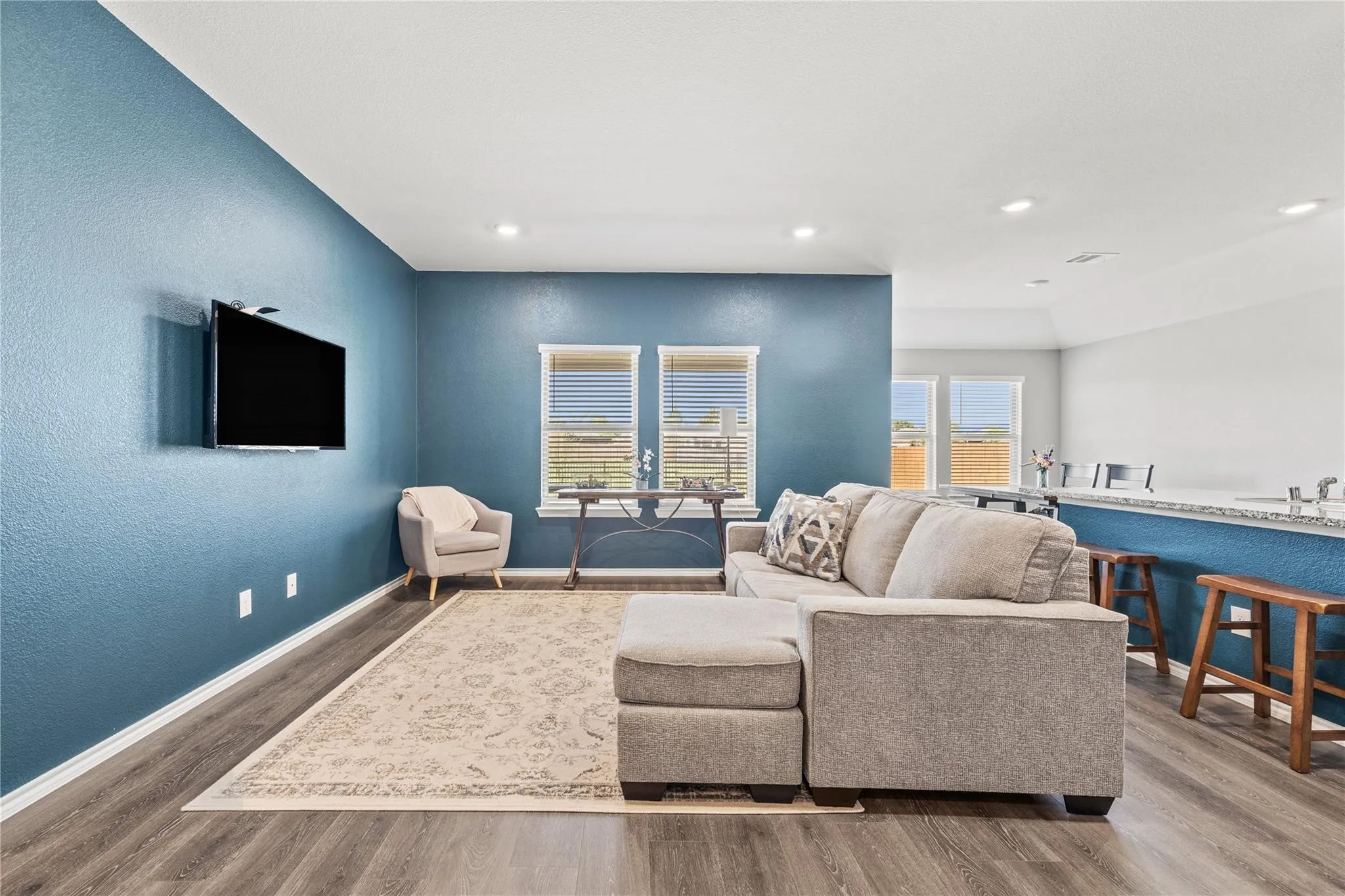 Open-concept living area with wood-finish flooring, recessed lighting, and multiple windows