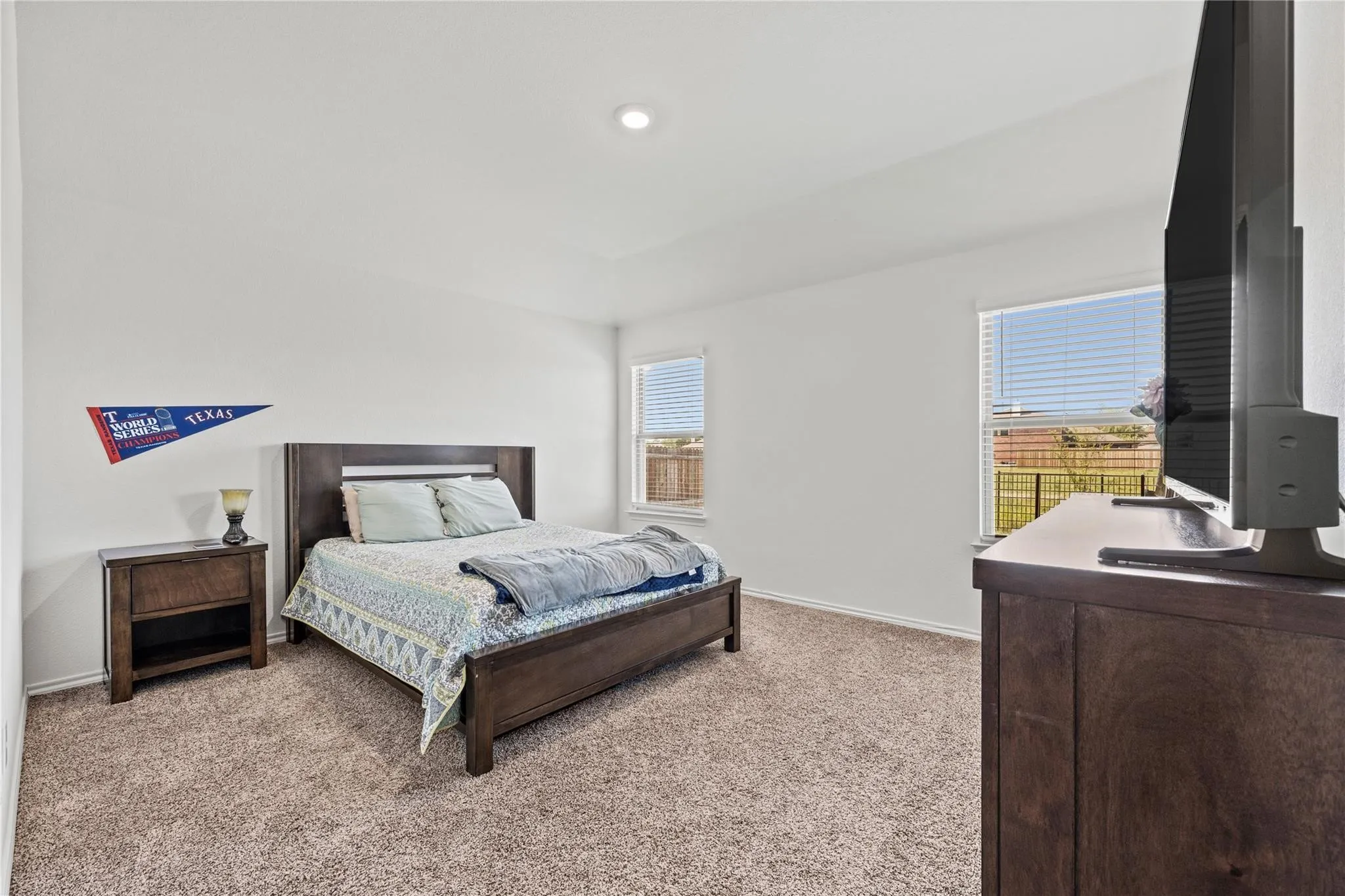 Recessed lighting, neutral carpeting, and dual windows with blinds