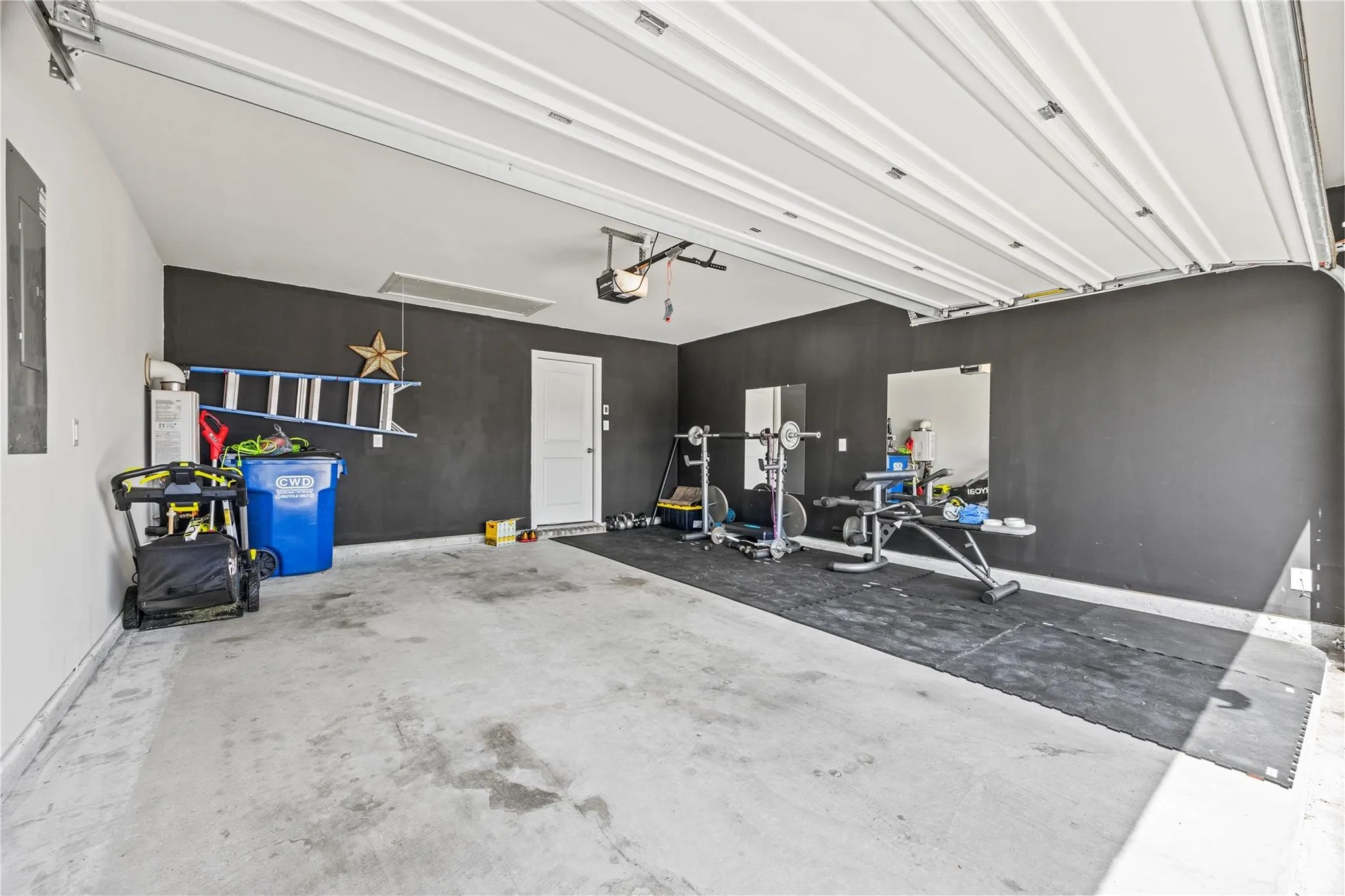 Attached garage with a roll-up door, concrete flooring, and a side access door