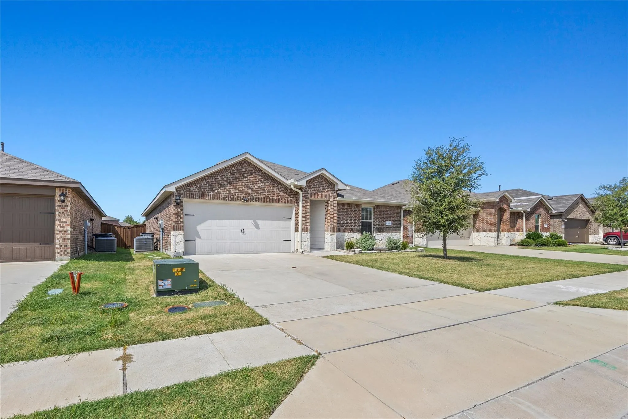 Brick and stone exterior with a two-car garage, concrete driveway, and front lawn