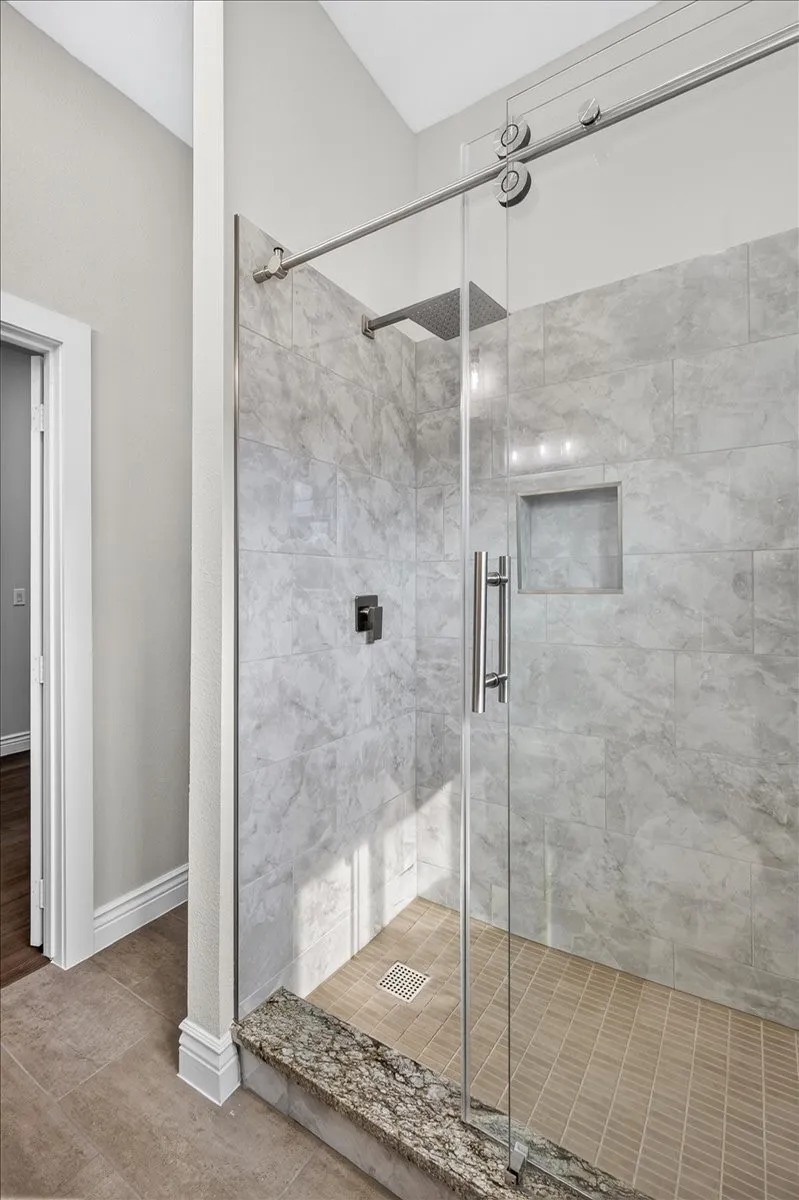 Walk-in shower with clear glass barn door style enclosure, a built-in shower niche, and a rain shower head