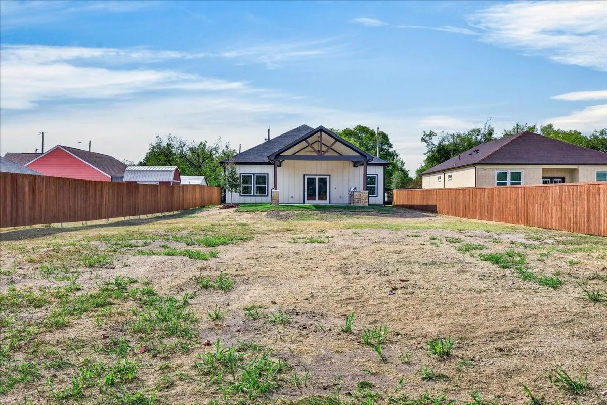 Spacious backyard with a wood privacy fence, featuring a covered patio with exposed beam detailing