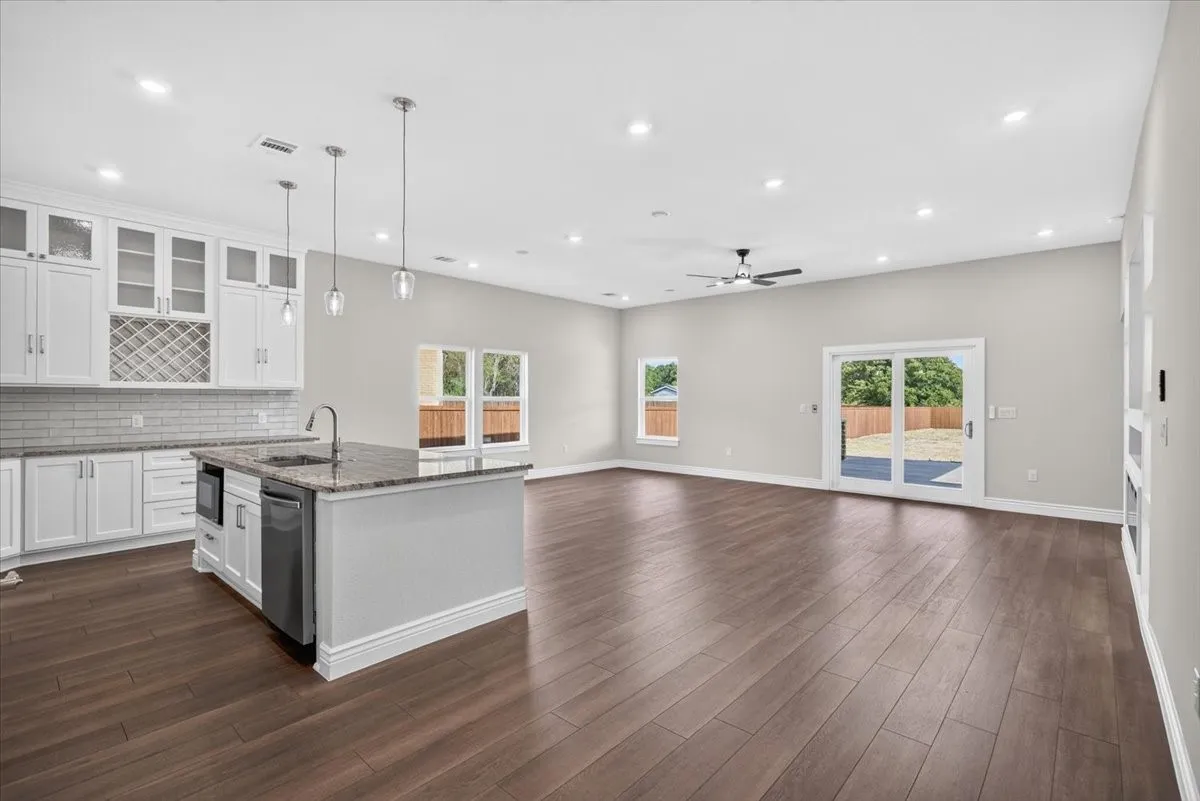 Kitchen island with integrated sink, stainless steel appliances, and pendant lighting