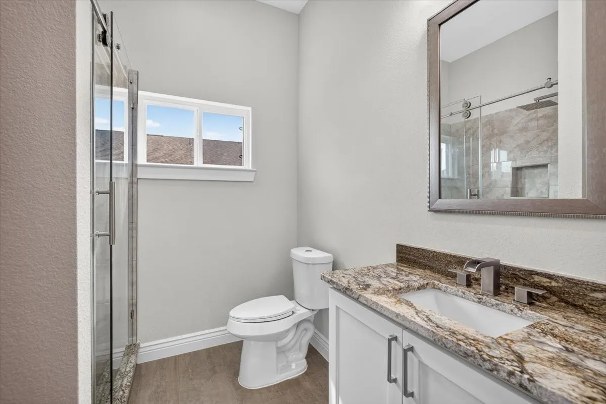 Vanity with a granite countertop, undermount sink, and brushed nickel faucet