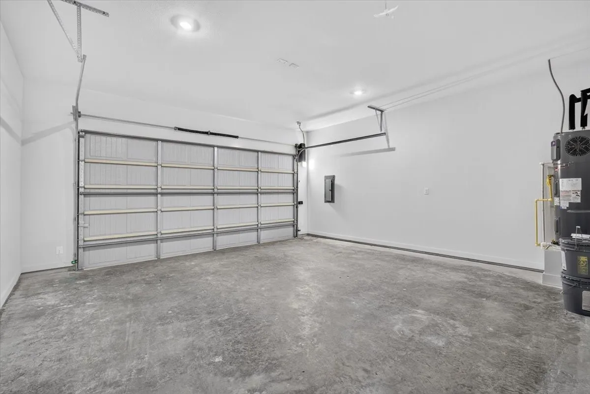 Concrete flooring, white painted walls, recessed lighting, and a roll-up garage door