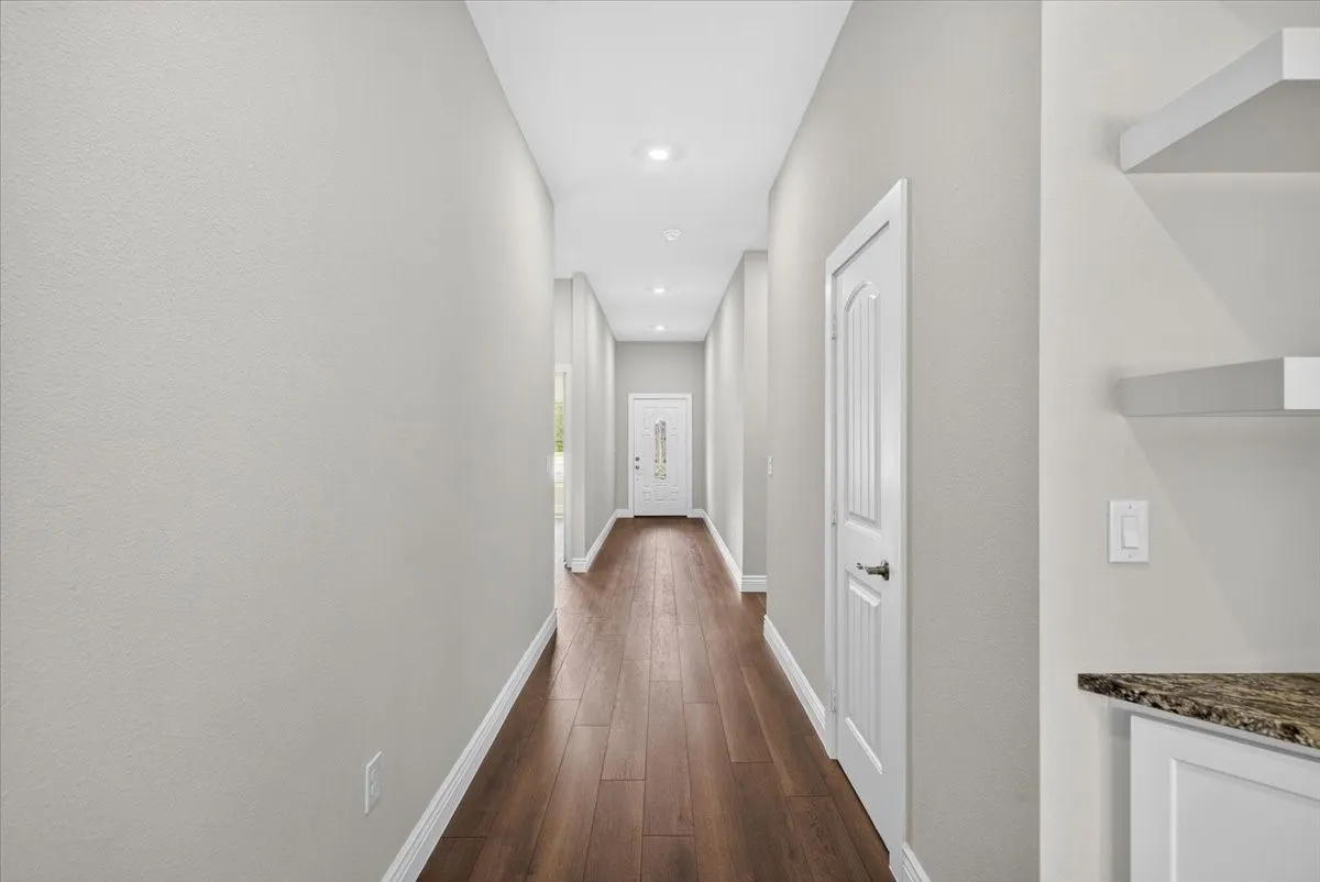 Hallway featuring wood-finish flooring, recessed lighting, and white paneled doors