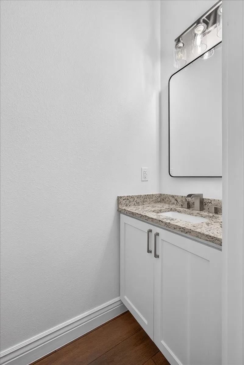 White vanity with dual cabinet doors, light-toned countertop, rectangular sink, and modern faucet
