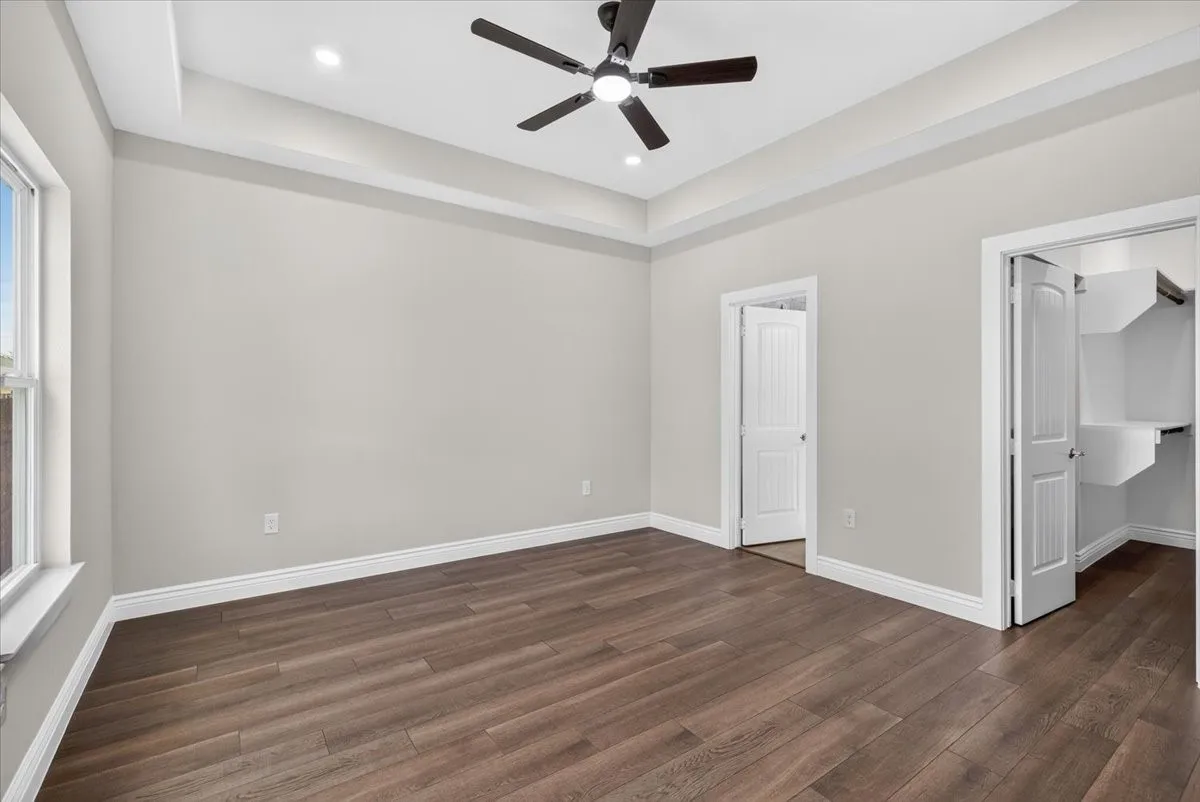 Tray ceiling with recessed lighting and a ceiling fan, wood-finish flooring, and white trim