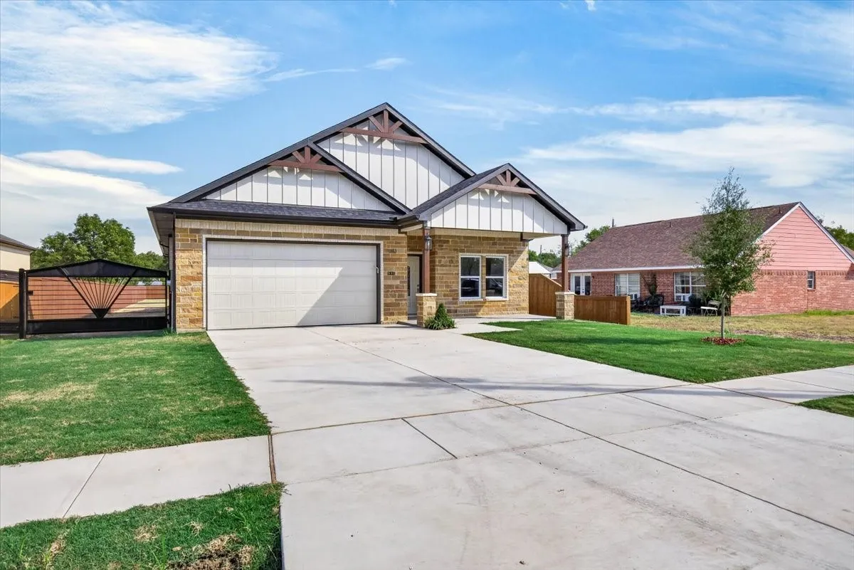 Contemporary facade featuring stone and vertical siding, a two-car garage, and a concrete driveway