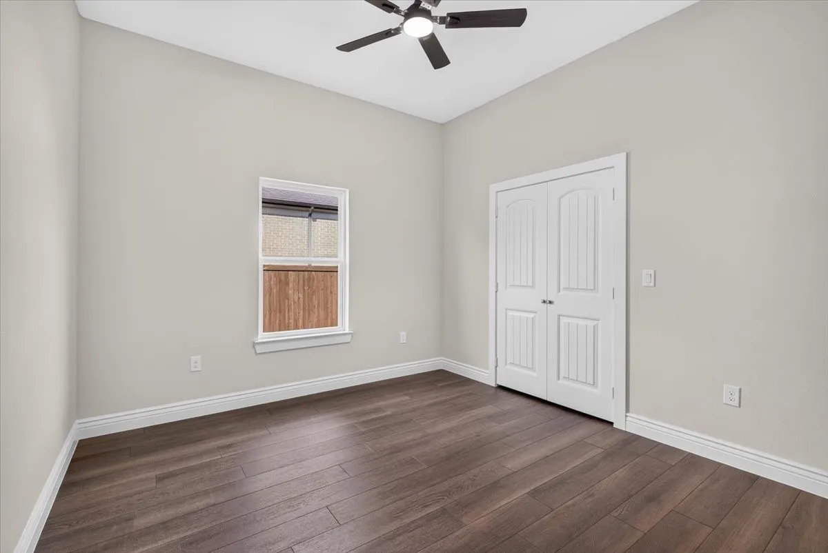 Vaulted ceiling with a ceiling fan, wood-finish flooring, and white trim