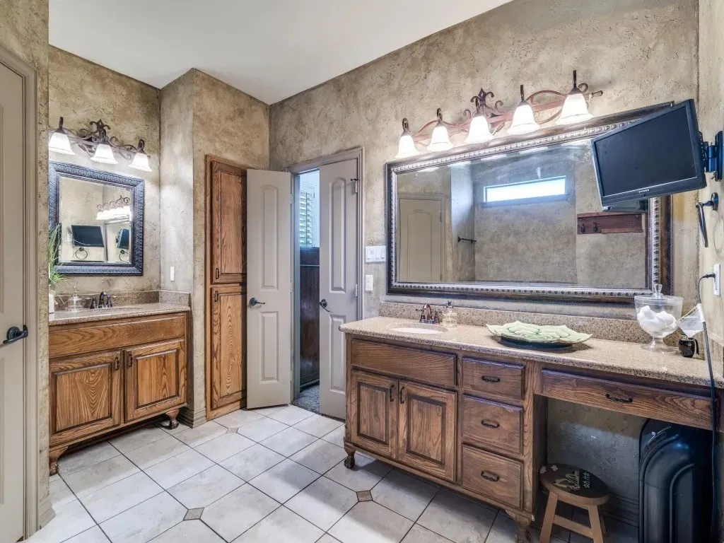 Dual wood-finish vanities with light-colored countertops, large framed mirrors, and multiple light fixtures