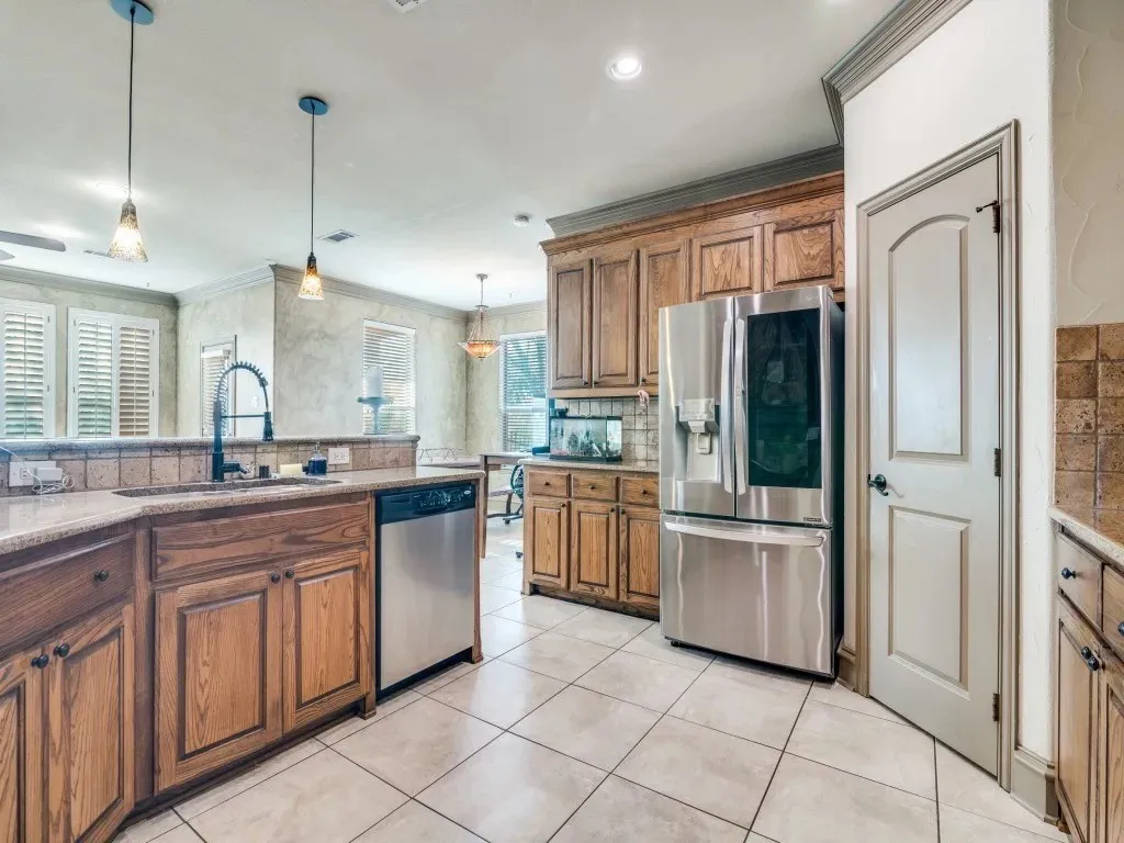 Kitchen featuring wood cabinetry, stainless steel appliances, tile flooring, and pendant lighting