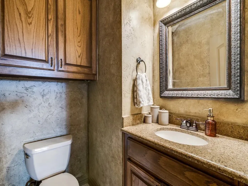 Wood cabinetry, framed mirror, vanity with integrated sink, and textured wall finish