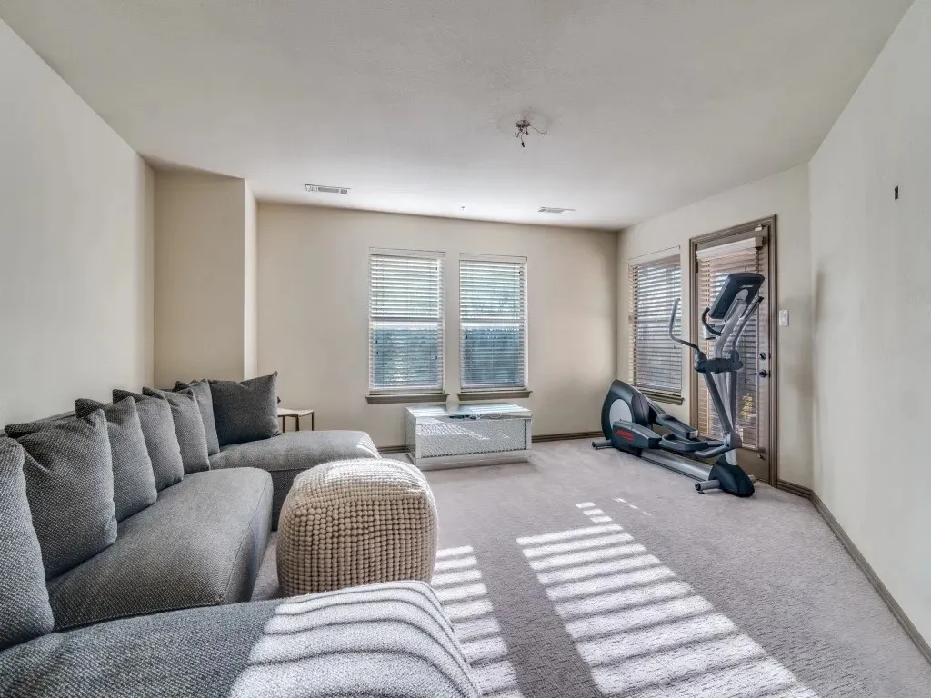 Spacious room featuring multiple windows with blinds, a door with a window, and light-toned wall-to-wall carpeting