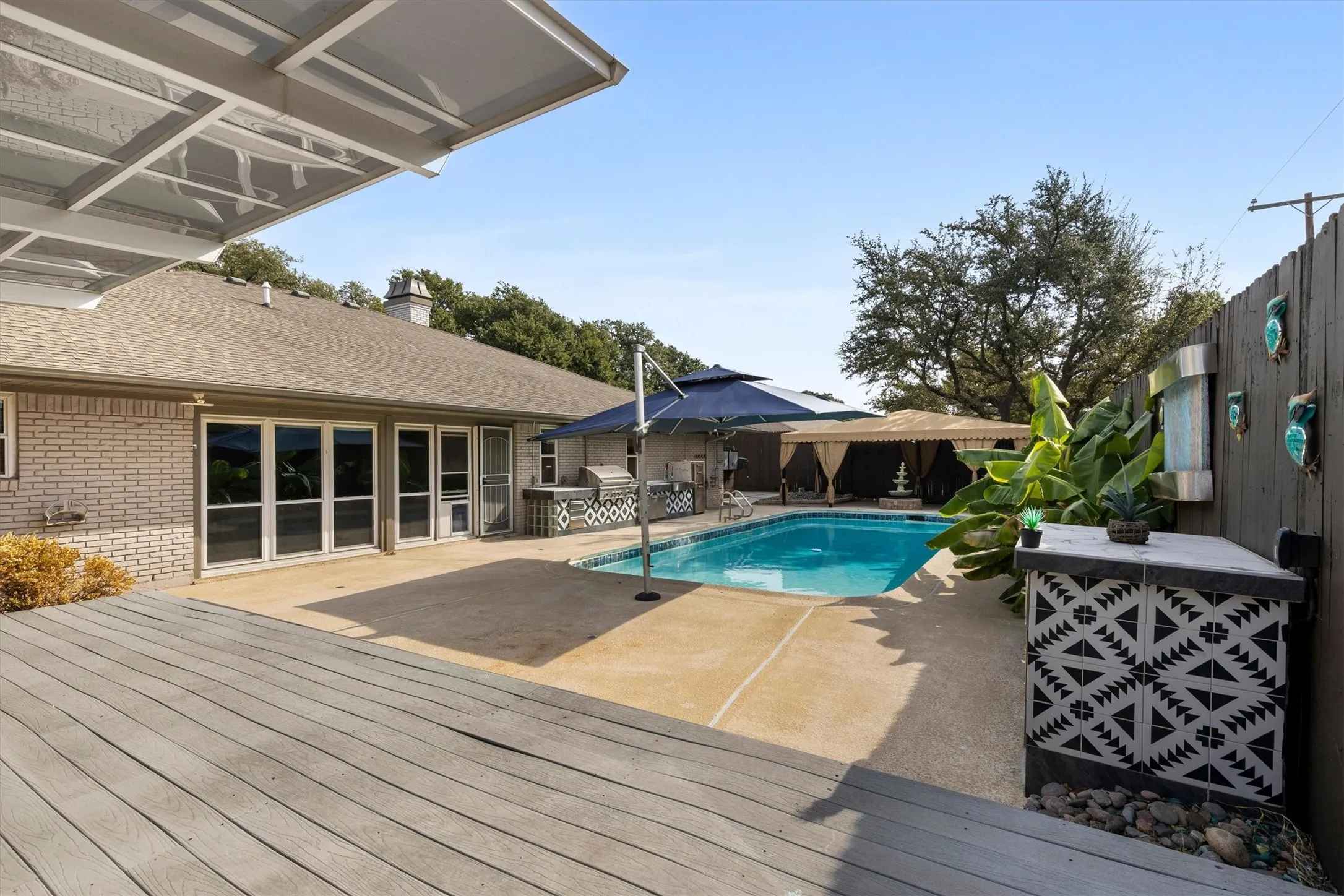 Expansive outdoor living area featuring a swimming pool, concrete patio, and a wood-finish deck