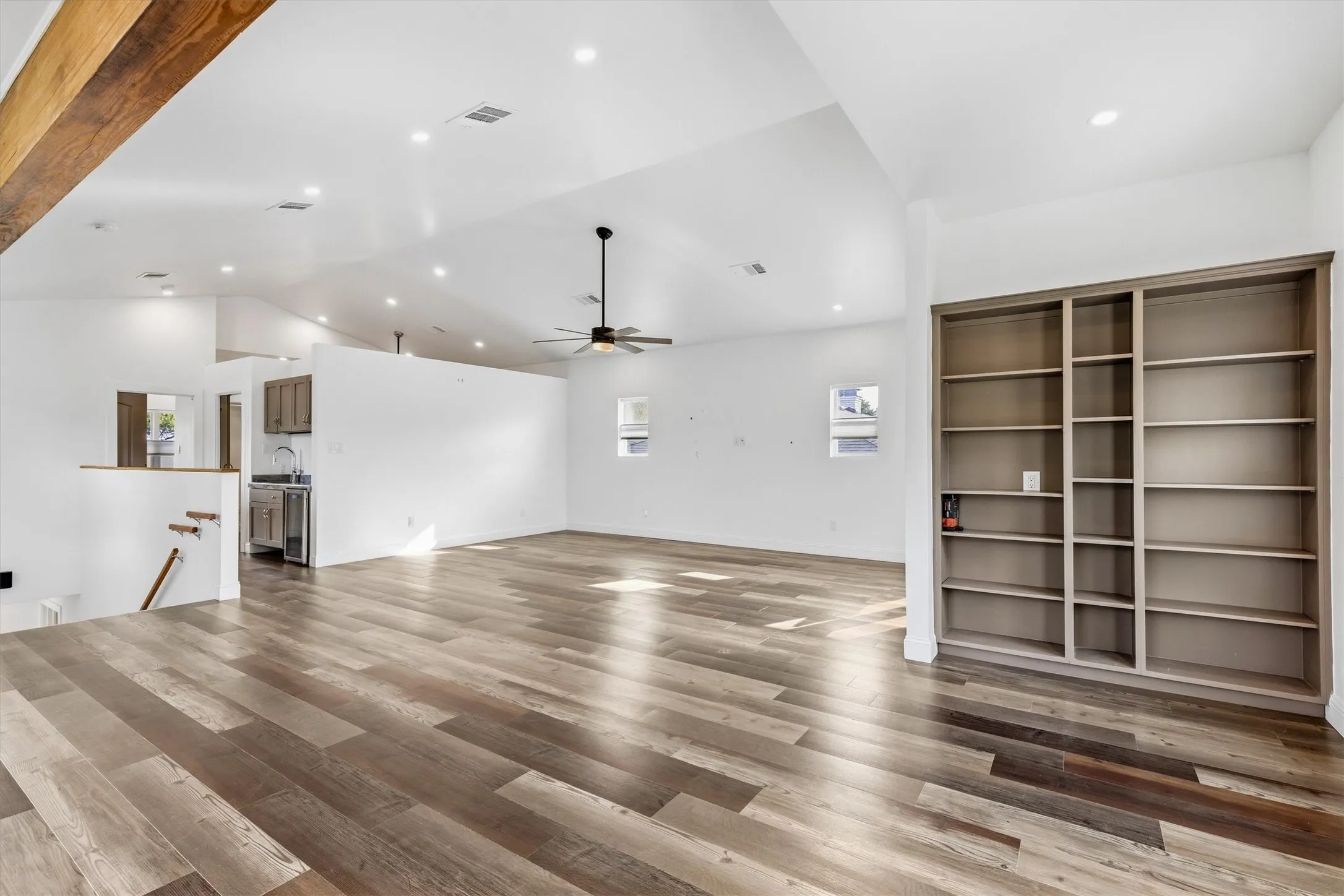 Wood-finish flooring, built-in shelving, vaulted ceilings, recessed lighting, and a ceiling fan